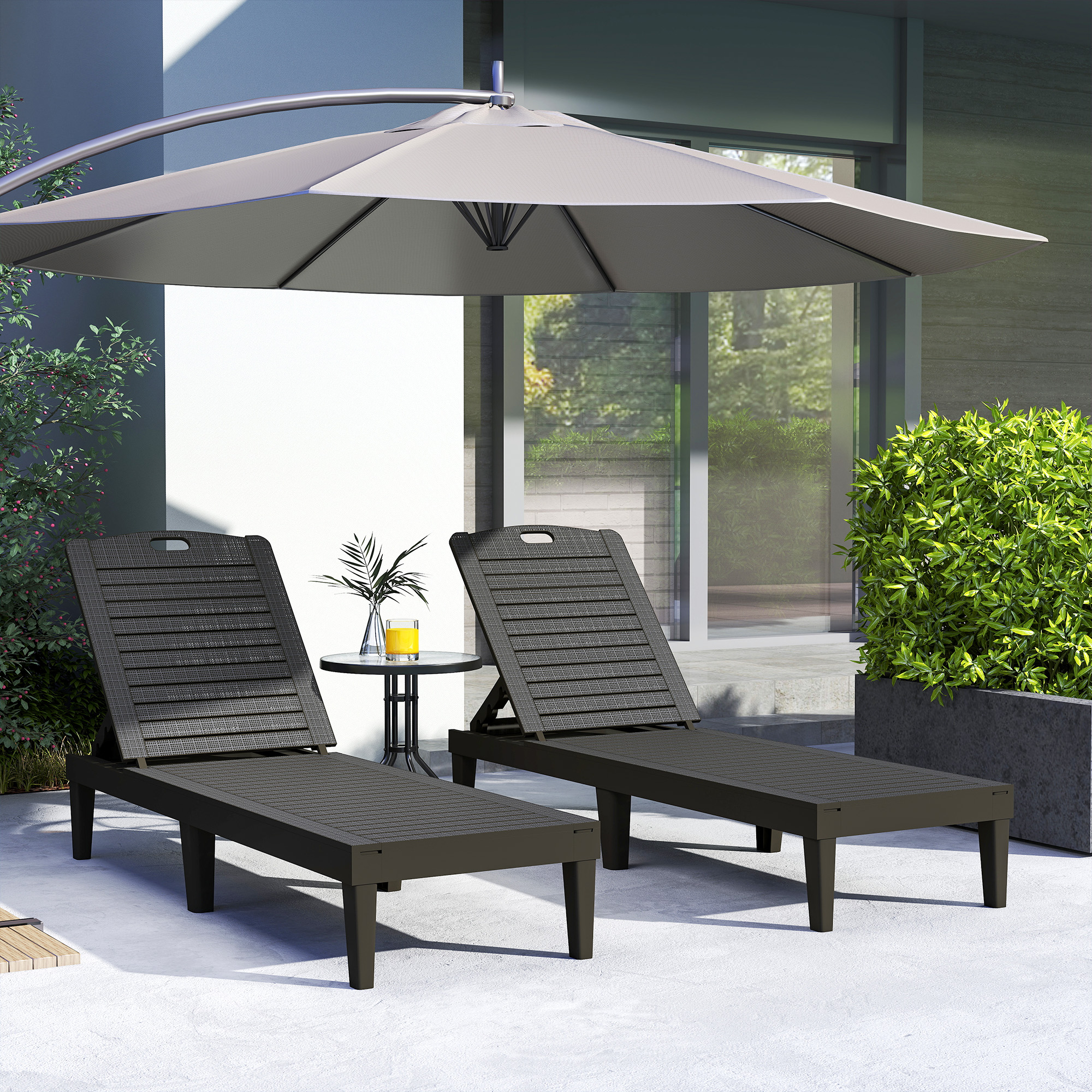 Dos tumbonas oscuras bajo un parasol en un patio, con una mesa con jugo cerca.