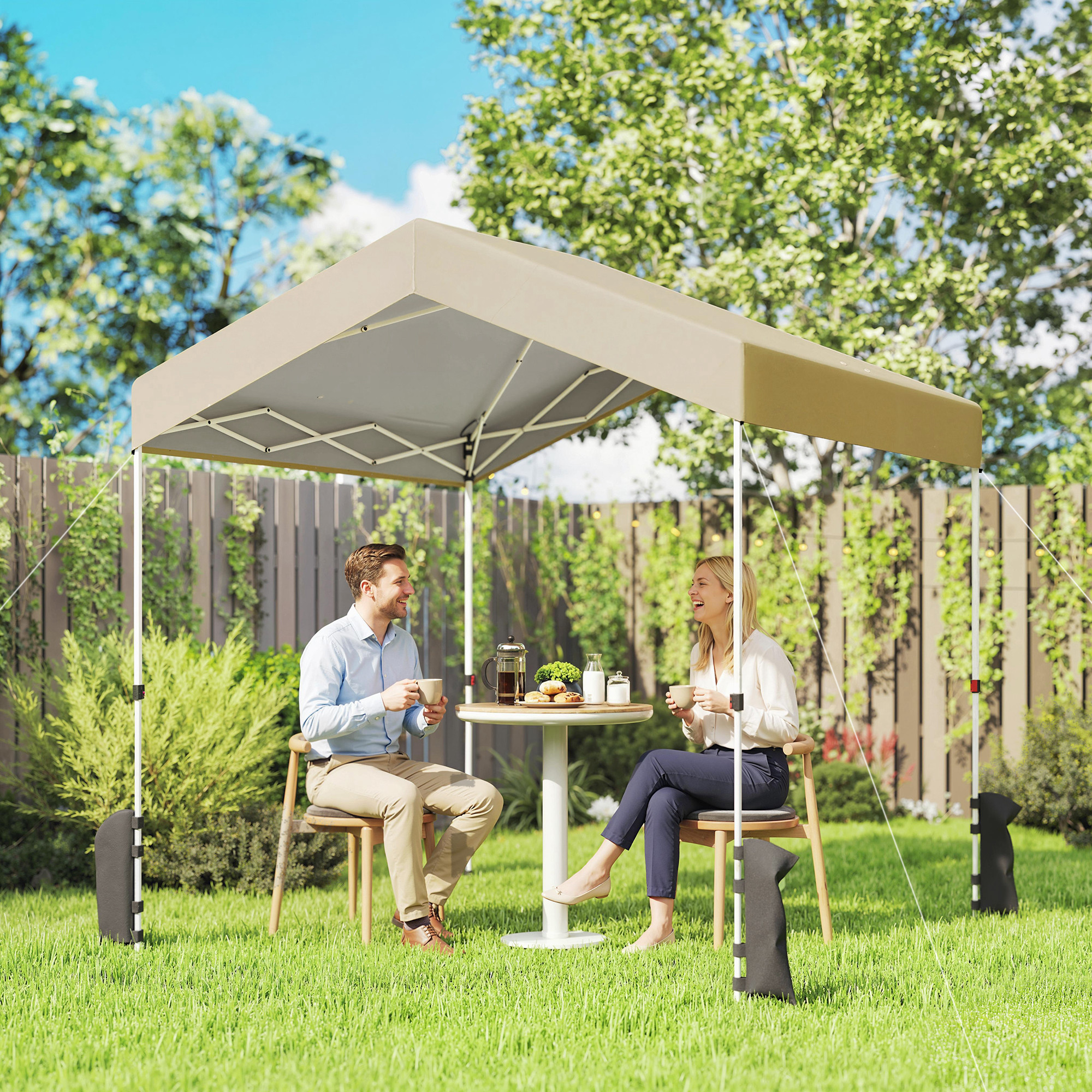 Una pareja disfruta de café bajo un toldo de jardín con una mesa llena de bocadillos.
