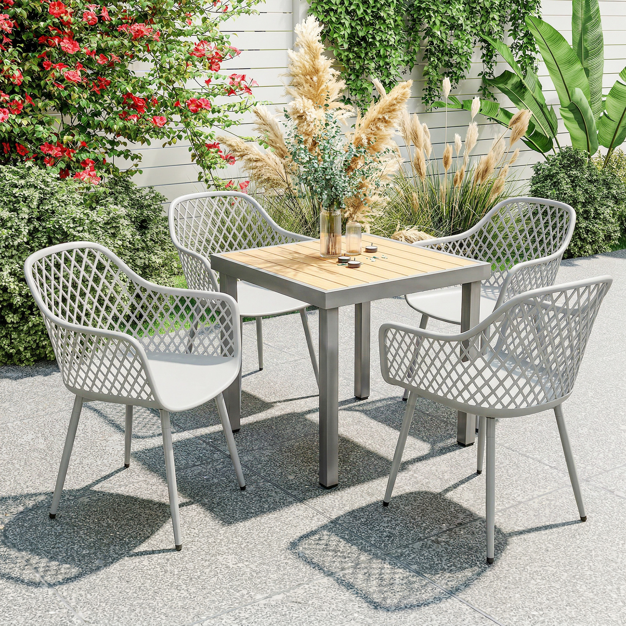 Mesa de jardín moderna con cuatro sillas en patio de piedra con flores y plantas.