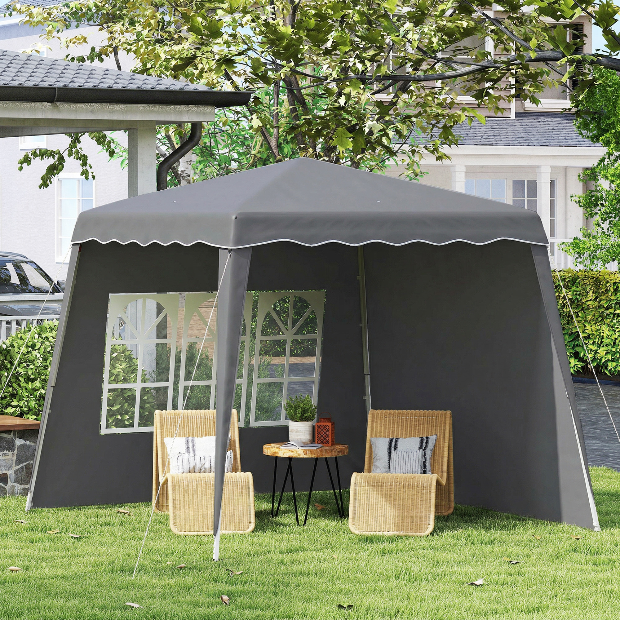 Una carpa gris con sillas de mimbre y una mesa en un césped.