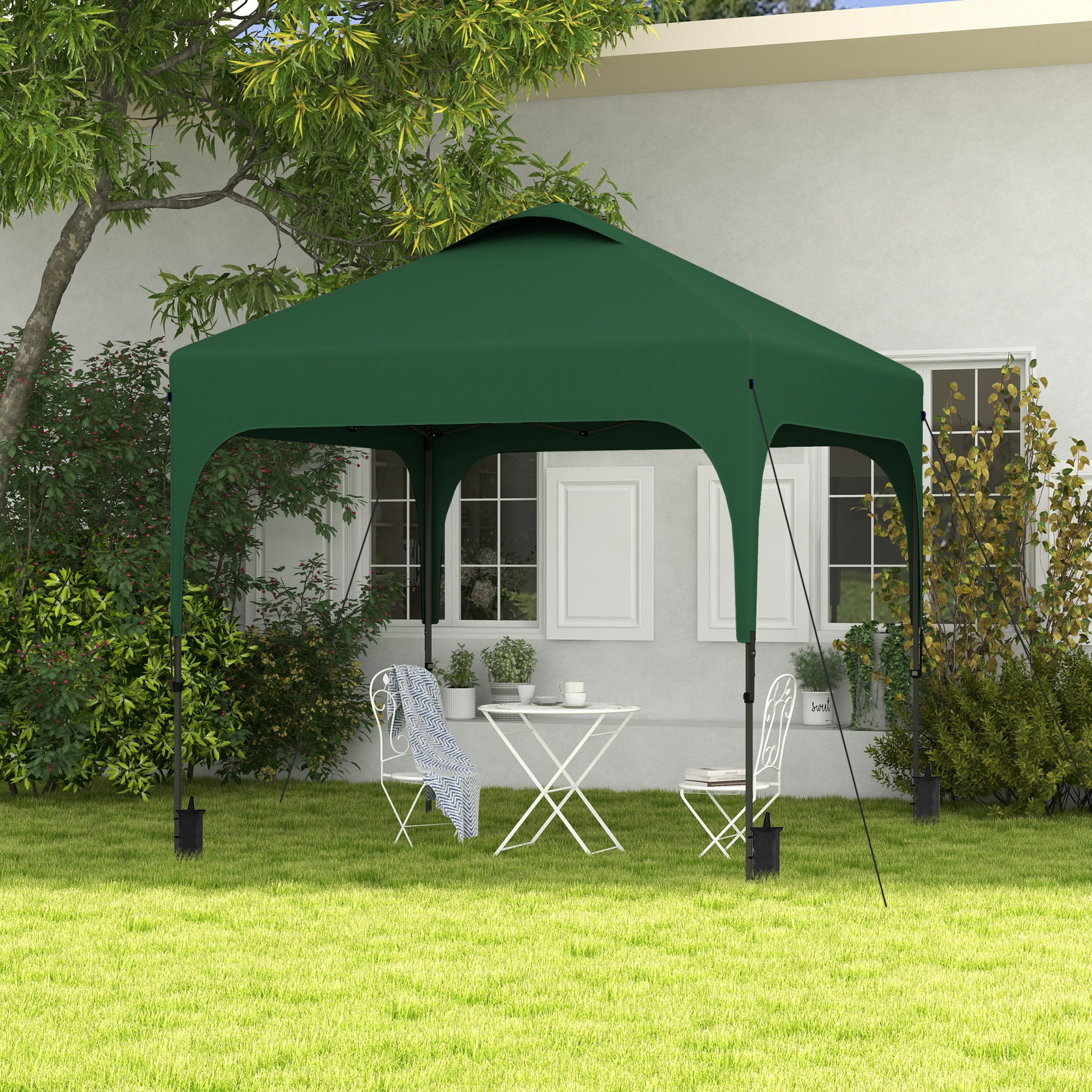 Gazebo verde en jardín con mesa, sillas y plantas.