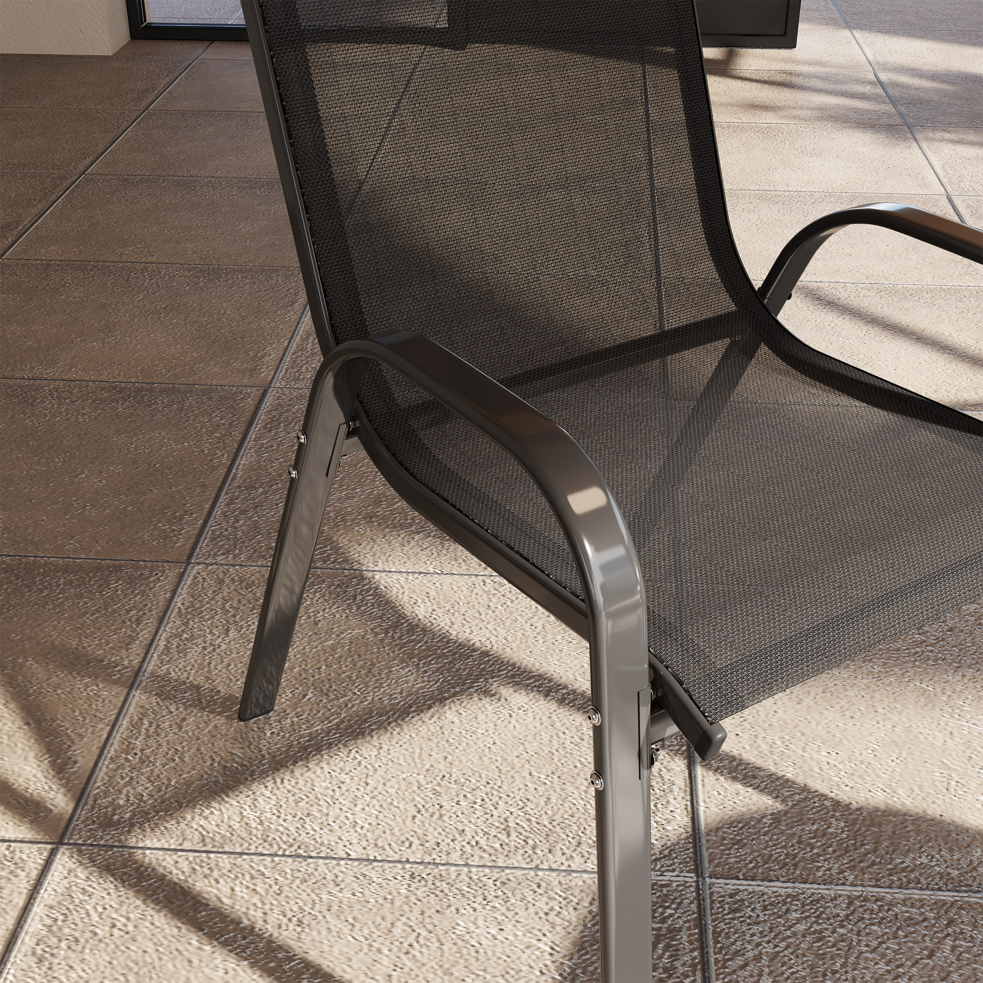 Una sedia in rete scura su un patio piastrellato con ombre.