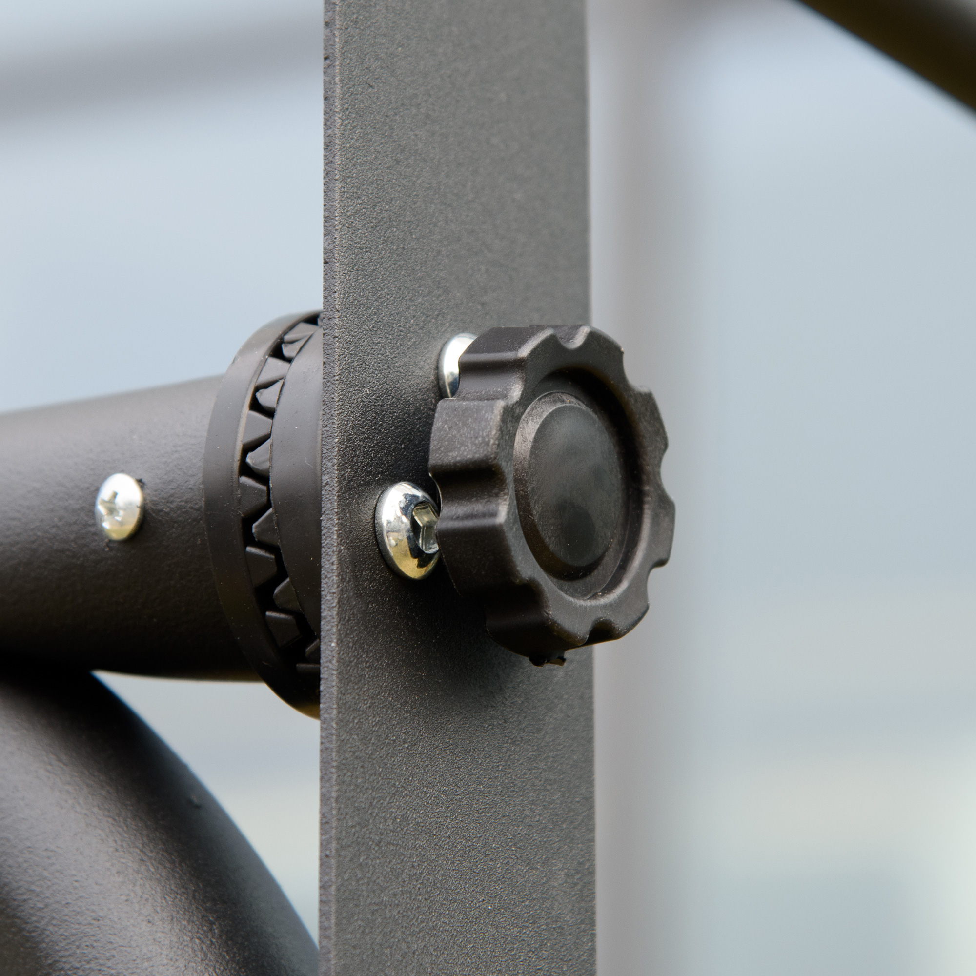 Primo piano di una manopola nera con viti su una barra di metallo.