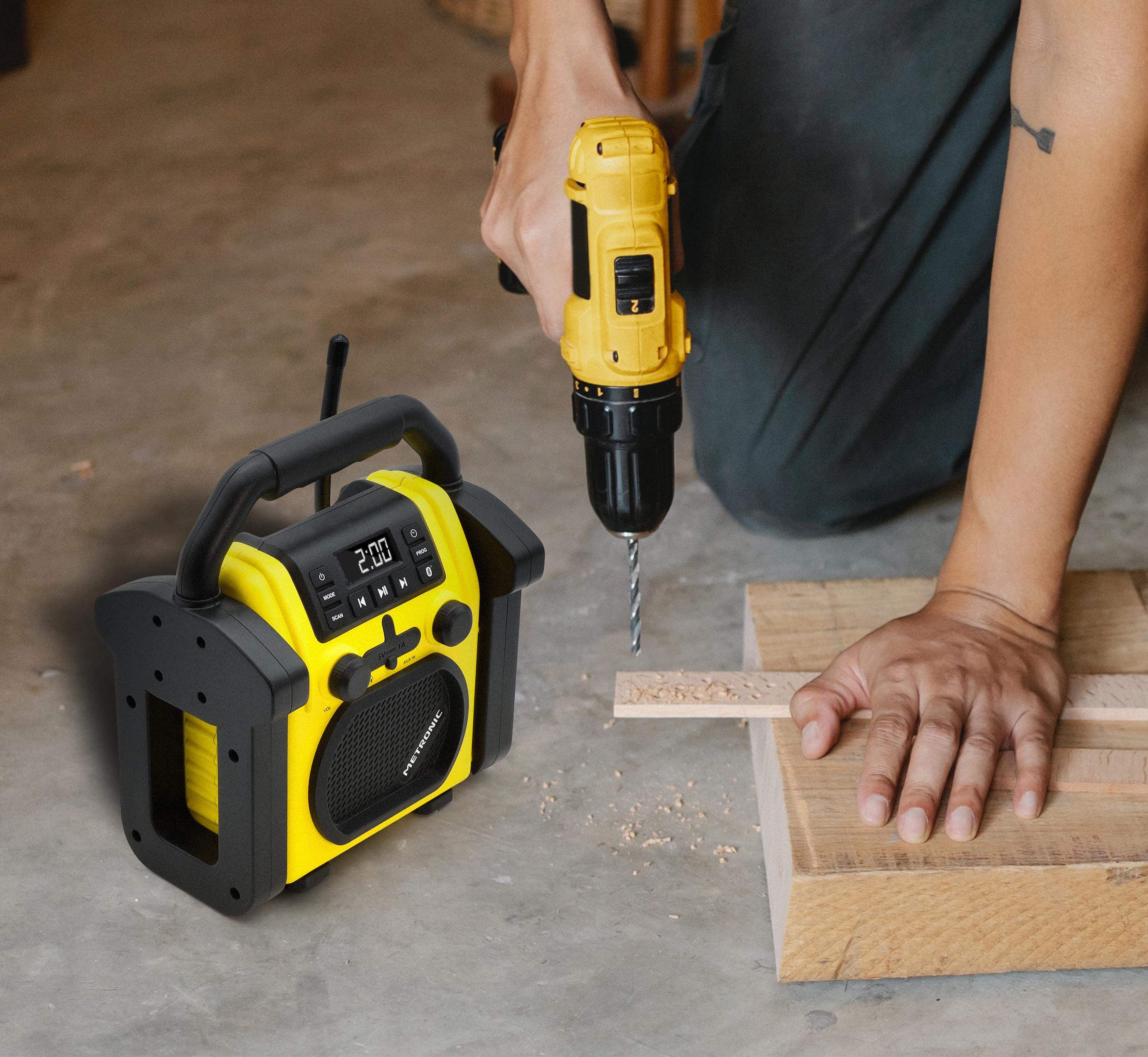 Un dispositivo combinado de radio y taladro, amarillo y negro, sobre suelo de hormigón.