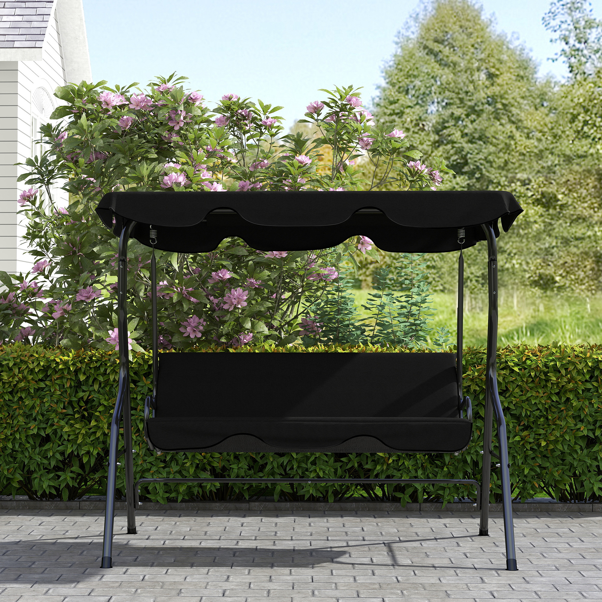 Un set di altalene nero si trova su un patio lastricato di fronte a cespugli in fiore.
