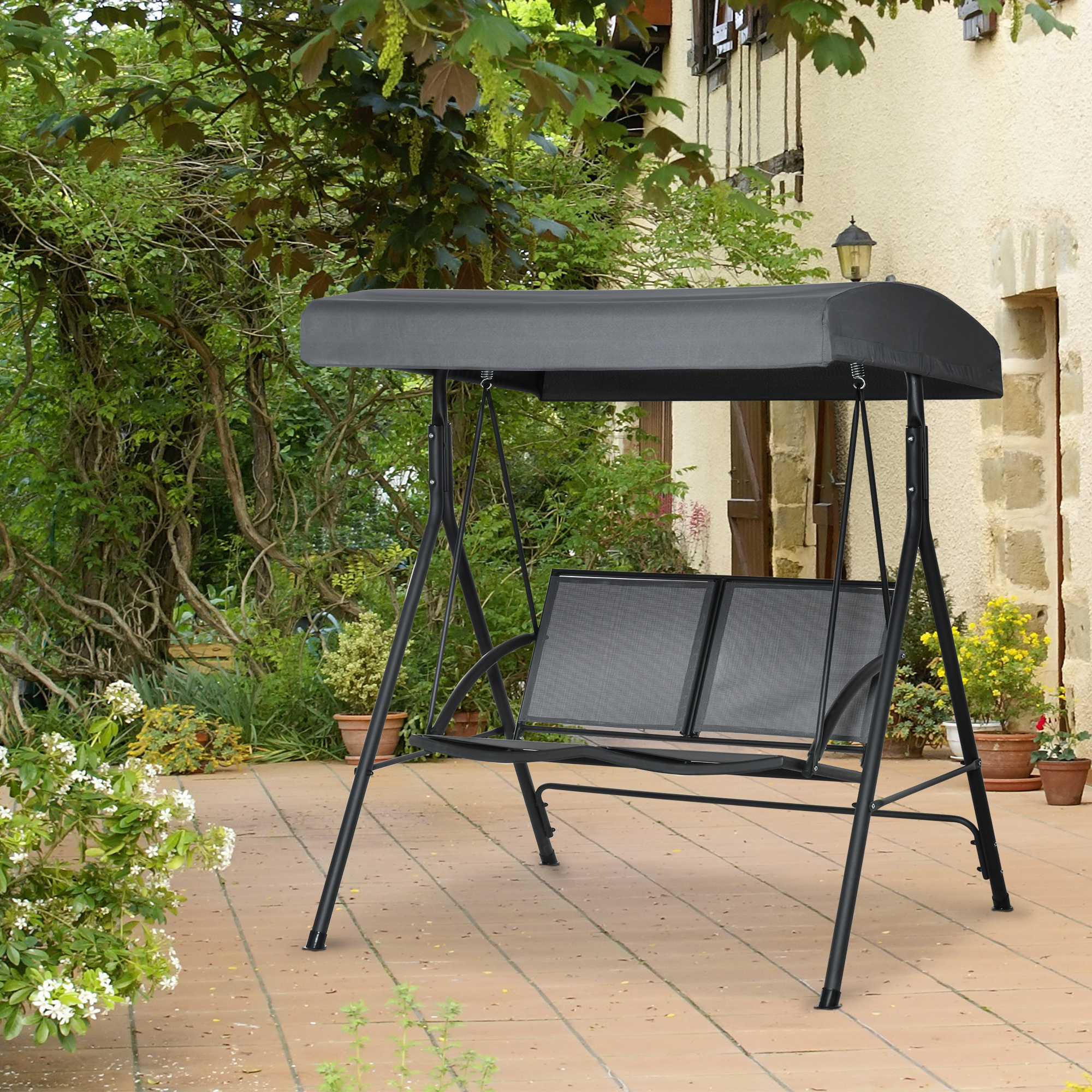 Un columpio negro con toldo gris se asienta sobre un patio pavimentado.