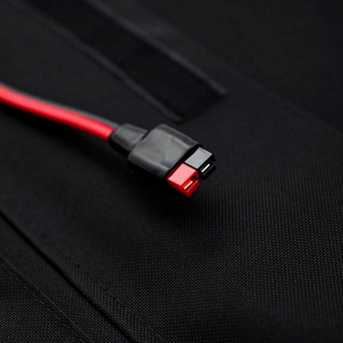 Ein rotes und schwarzes Kabel mit einem Stecker auf schwarzem Hintergrund.