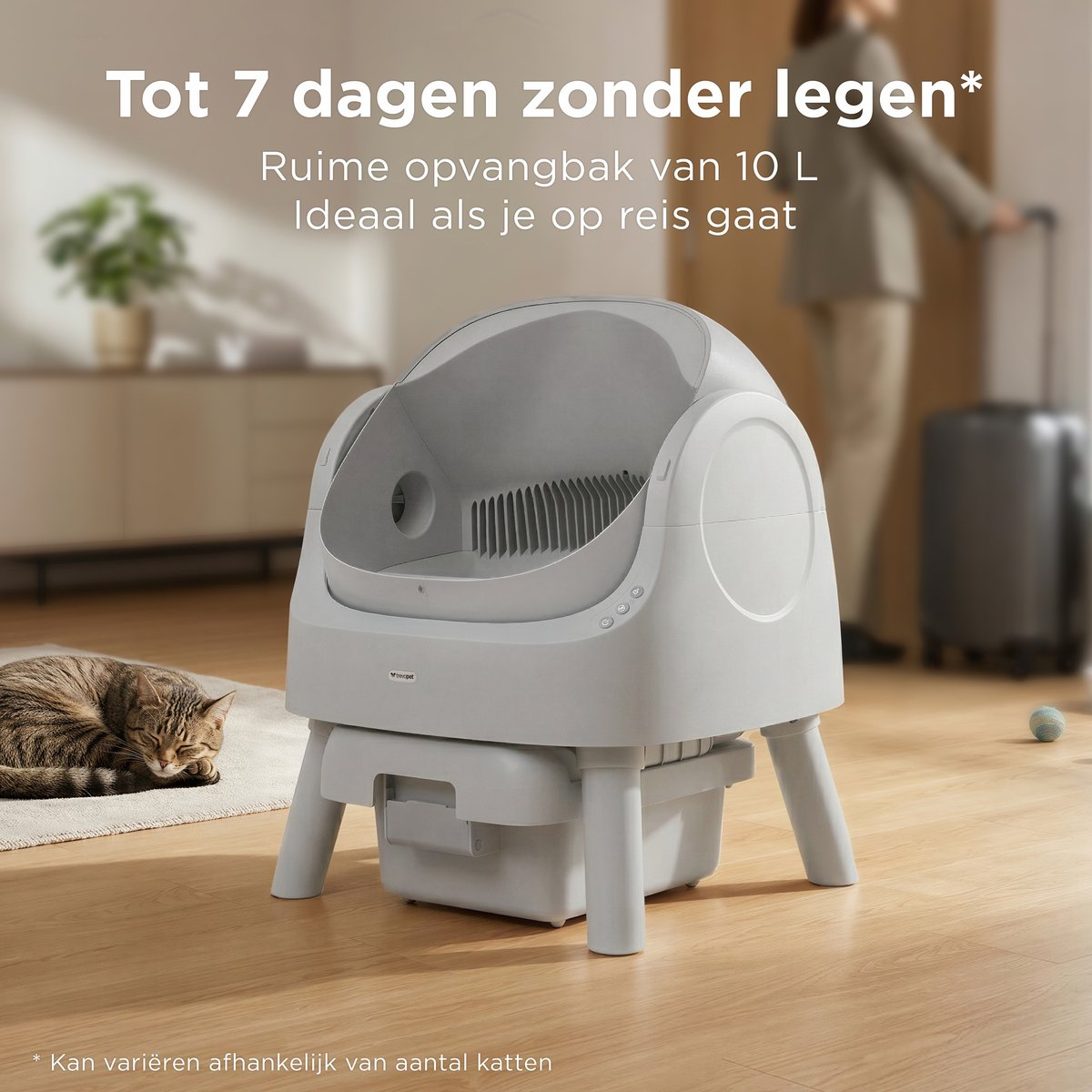 Een kat slaapt naast een automatische kattenbak in huis.