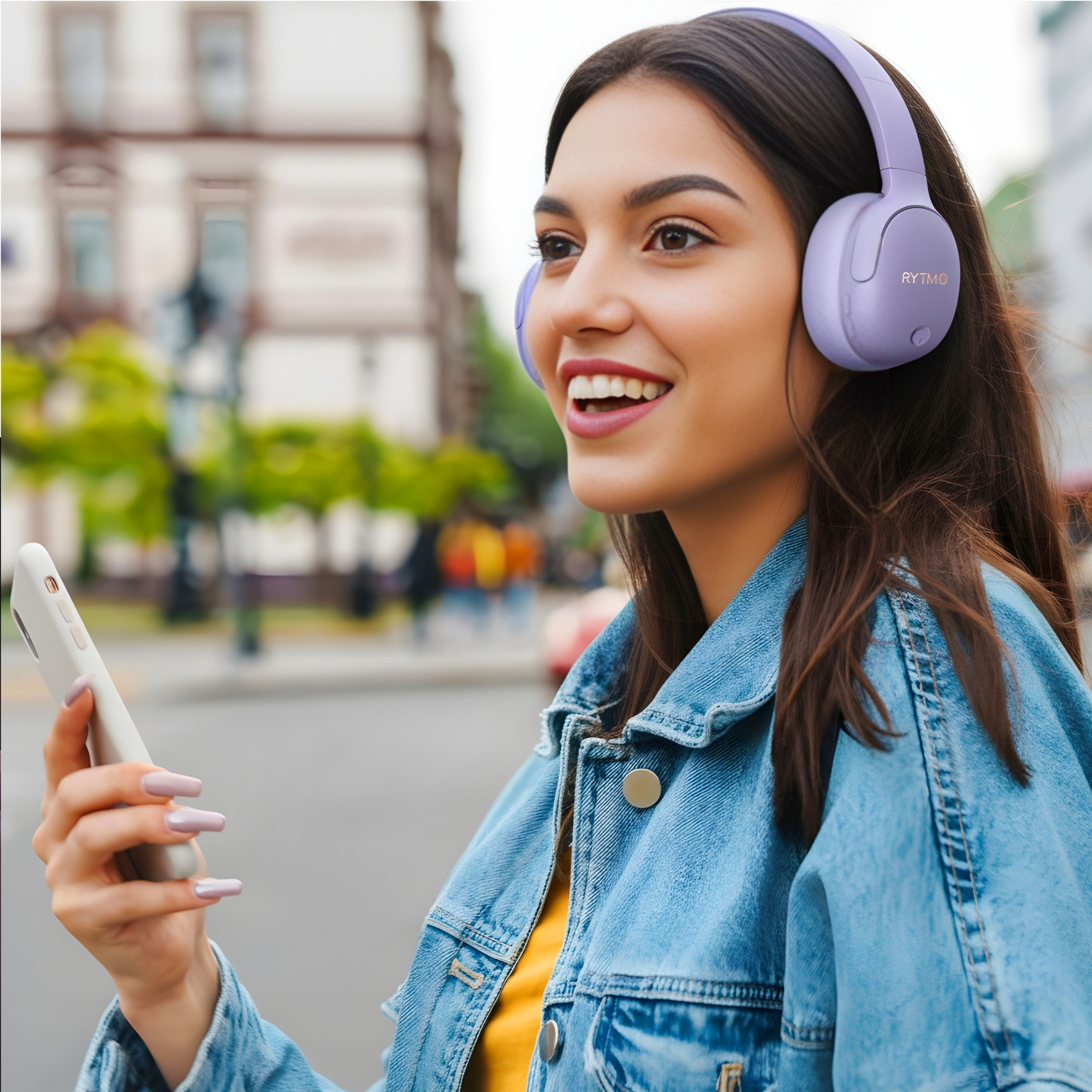 Kobieta w fioletowych słuchawkach trzymająca telefon.