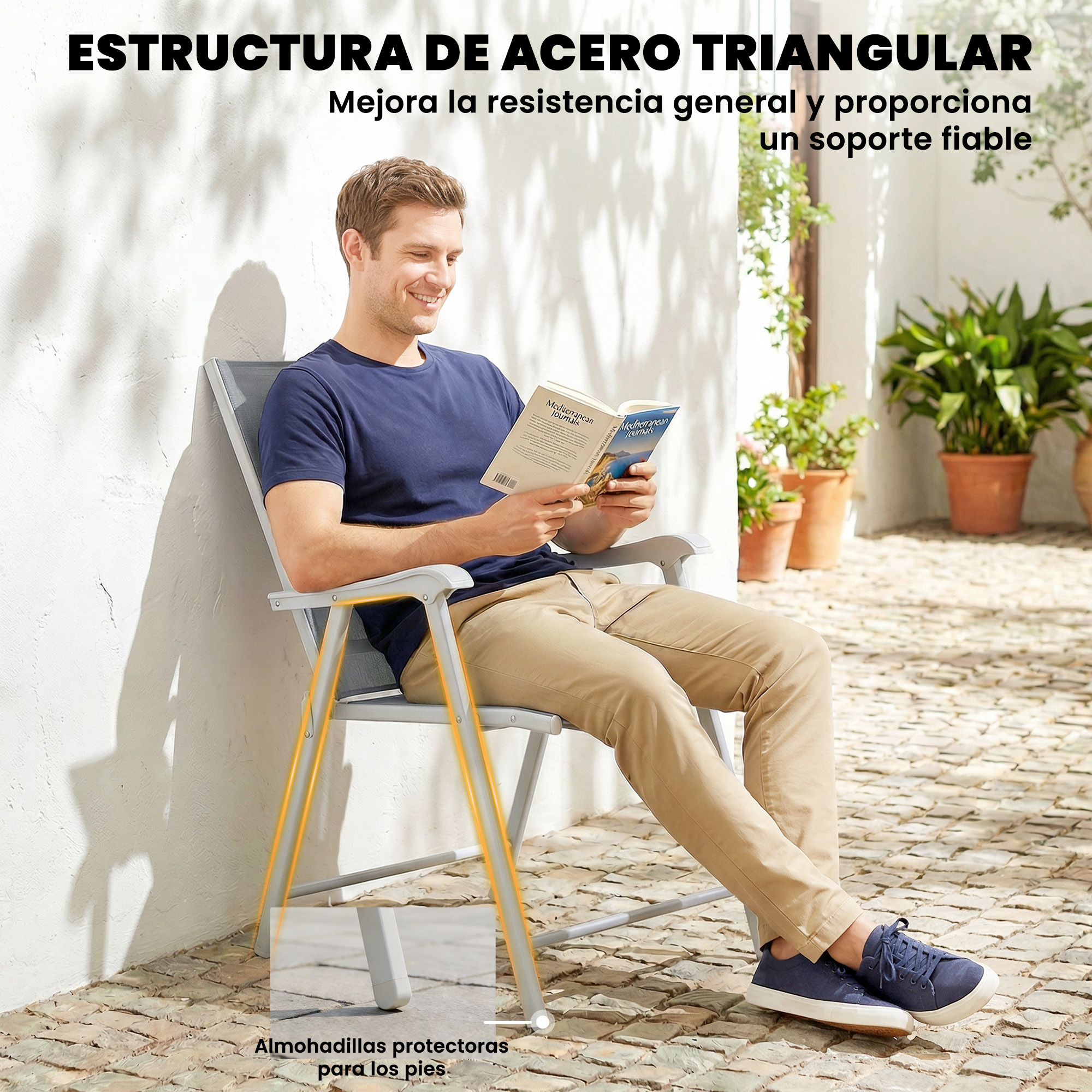 Un hombre sentado en una silla lee un libro. Viste camiseta azul y pantalones caqui.