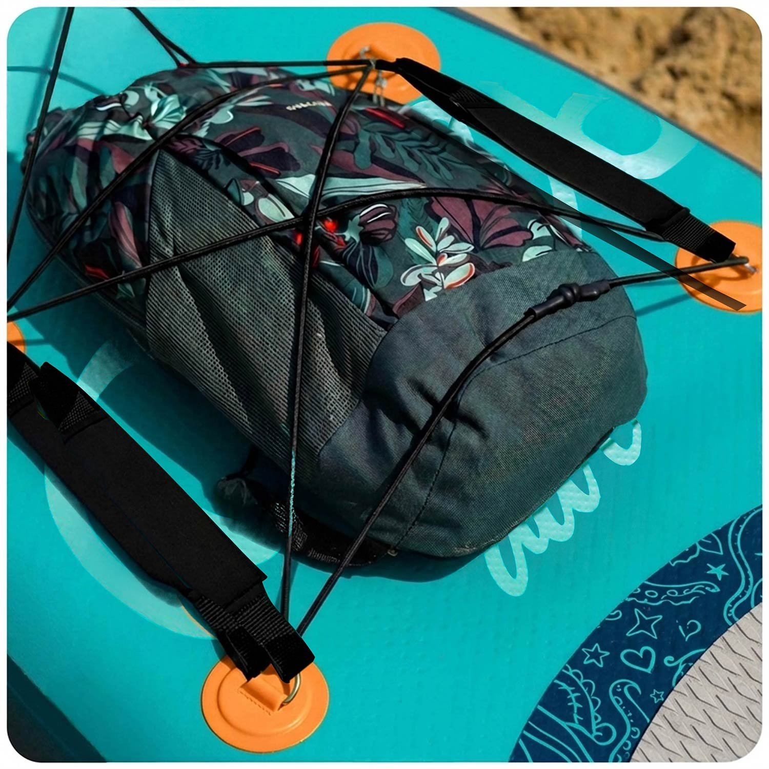 Ciemny plecak w kwiaty zabezpieczony czarnymi linkami bungee na turkusowej desce SUP.