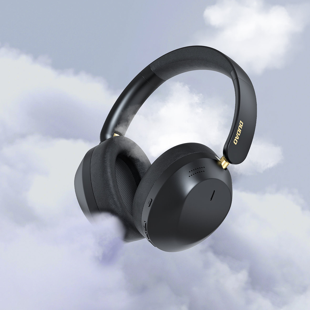 Cuffie nere con accenti dorati fluttuano contro un cielo nuvoloso.