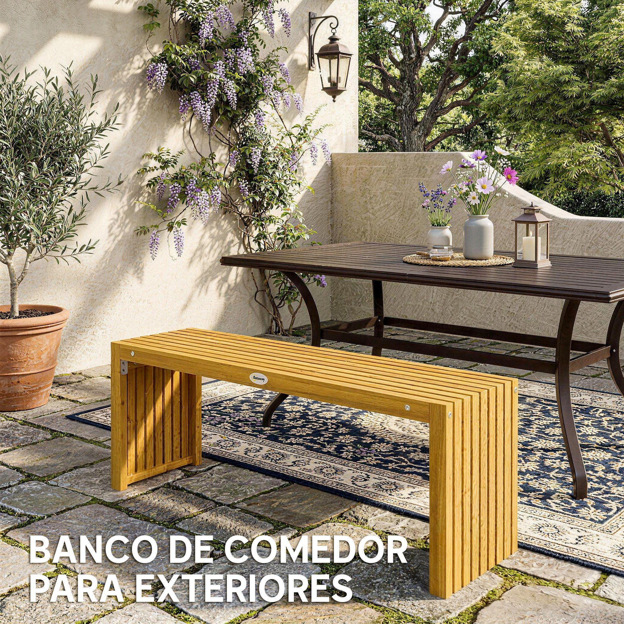 Banco y mesa de madera en patio de piedra con glicina en flor.