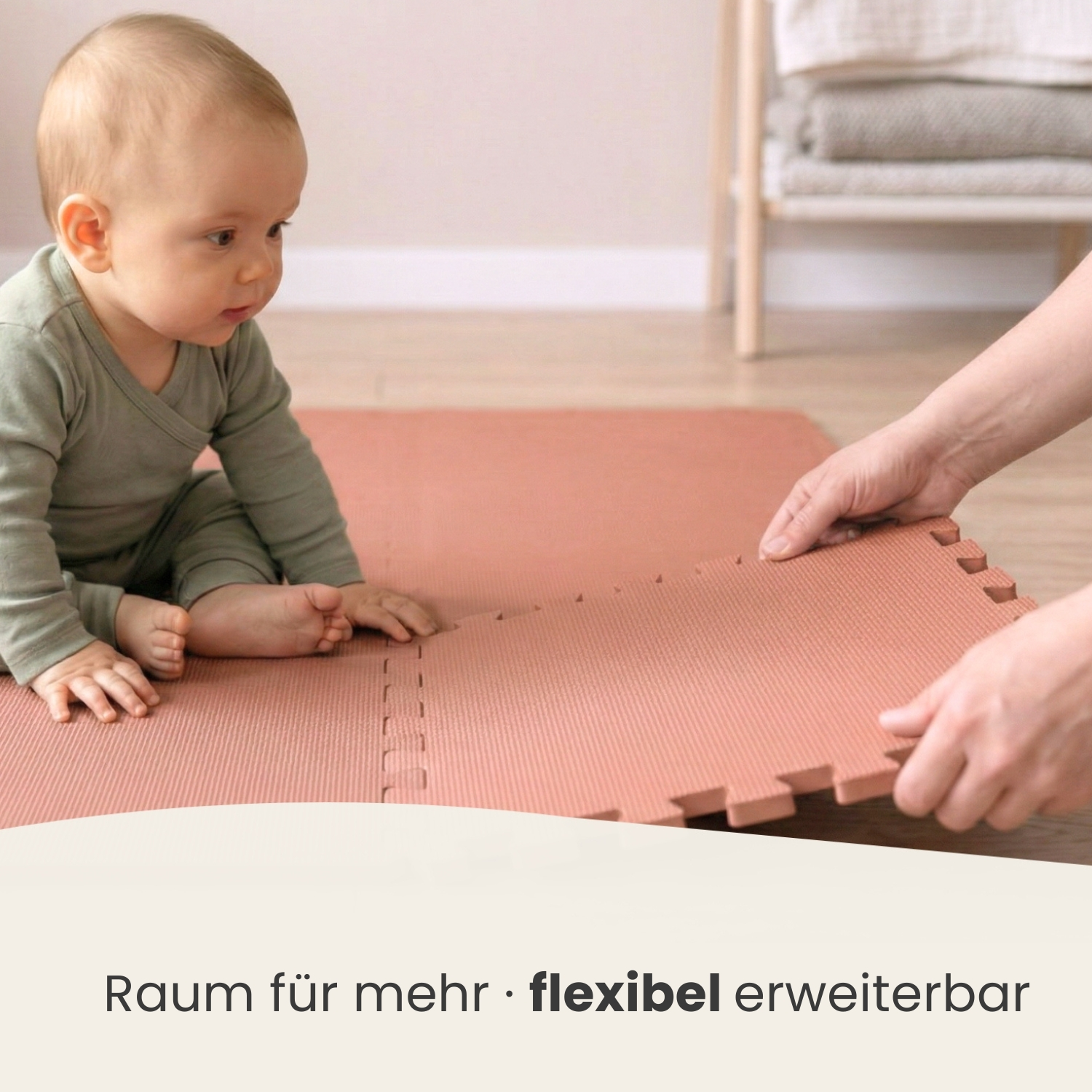 Ein Baby sitzt auf einer rosafarbenen Matte, während Hände eine weitere Matte anfügen.