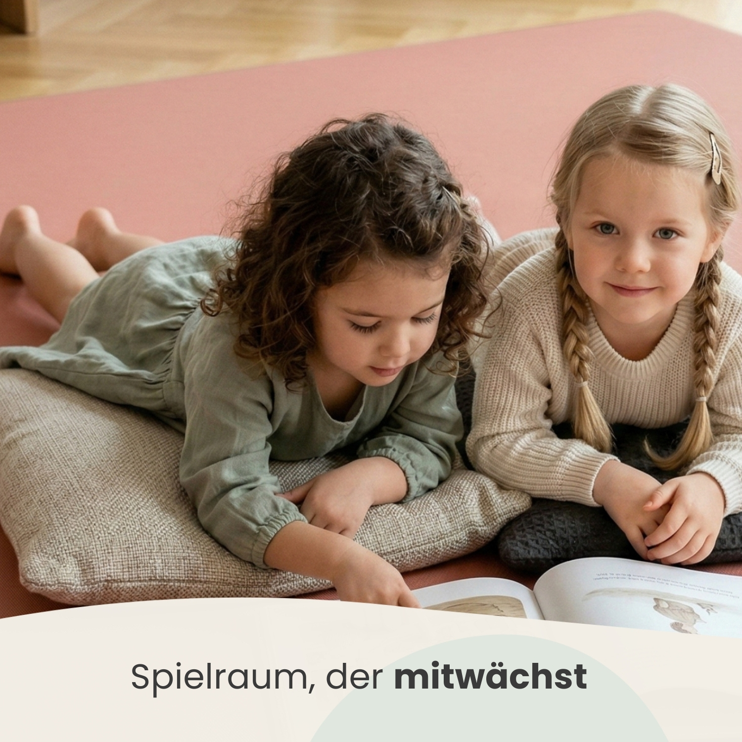 Zwei Mädchen liegen auf einem Teppich und lesen ein Buch.