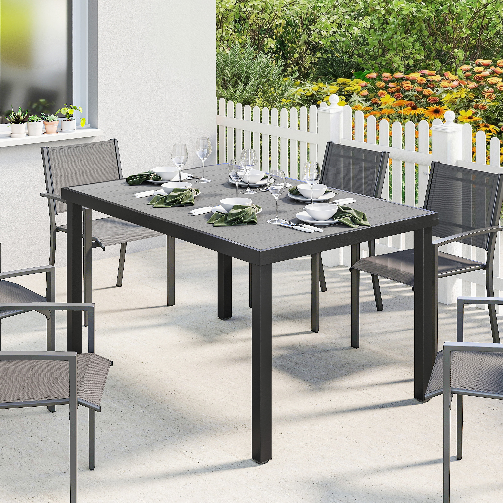 Una mesa de comedor gris con cuatro sillas en un patio, decorada con flores.