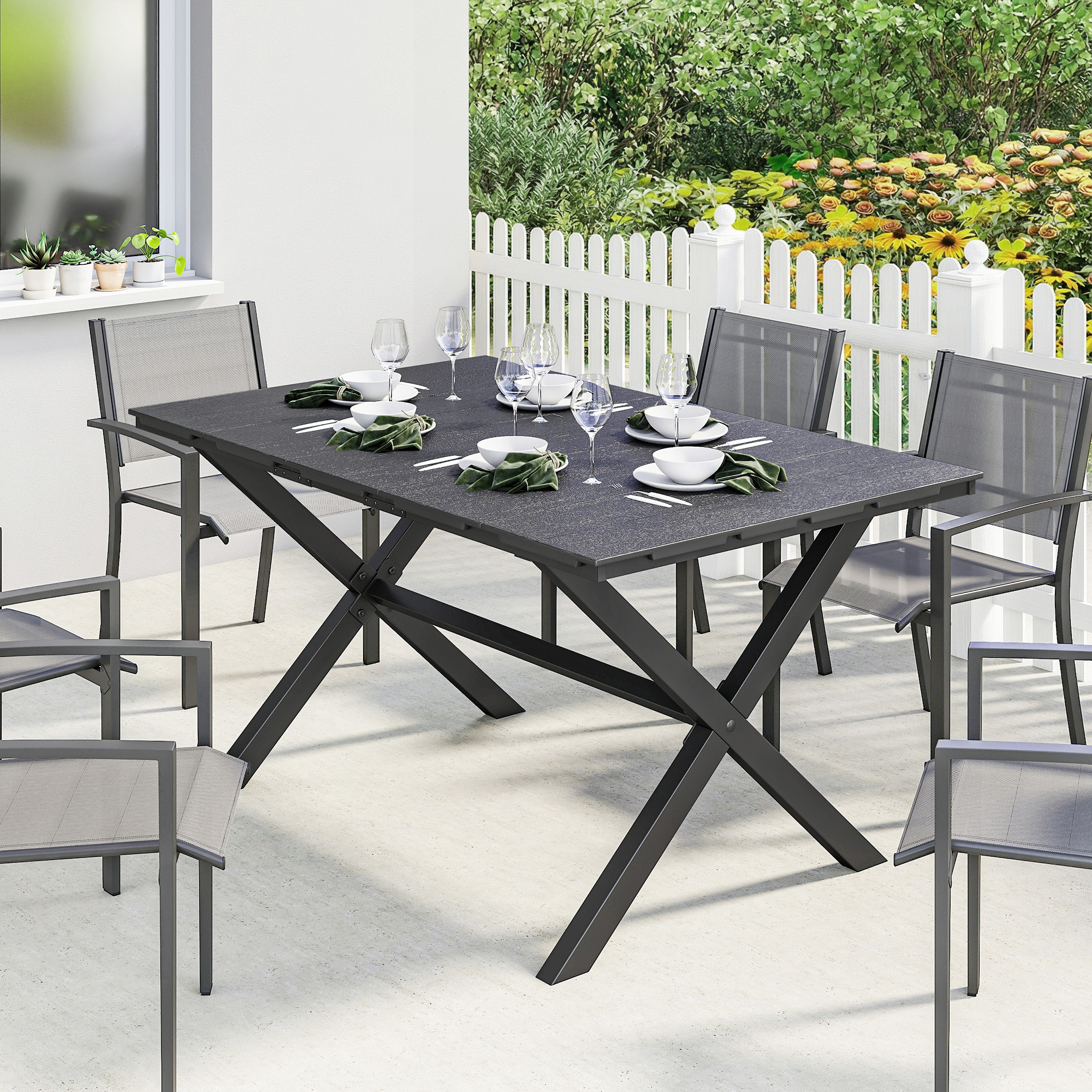 Una mesa de comedor exterior negra está puesta con seis sillas en un patio de hormigón.