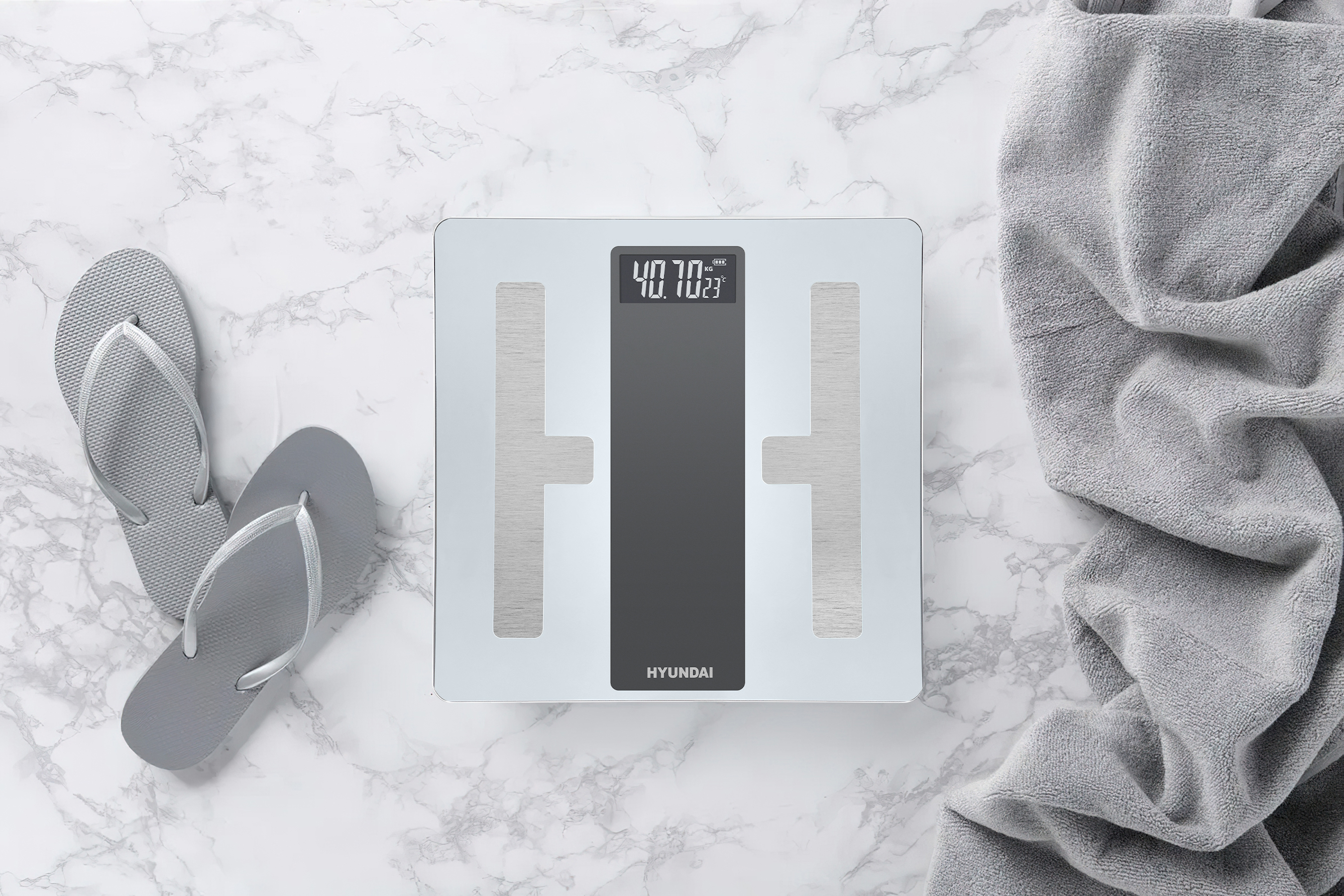 A digital scale with flip-flops and a towel on marble.