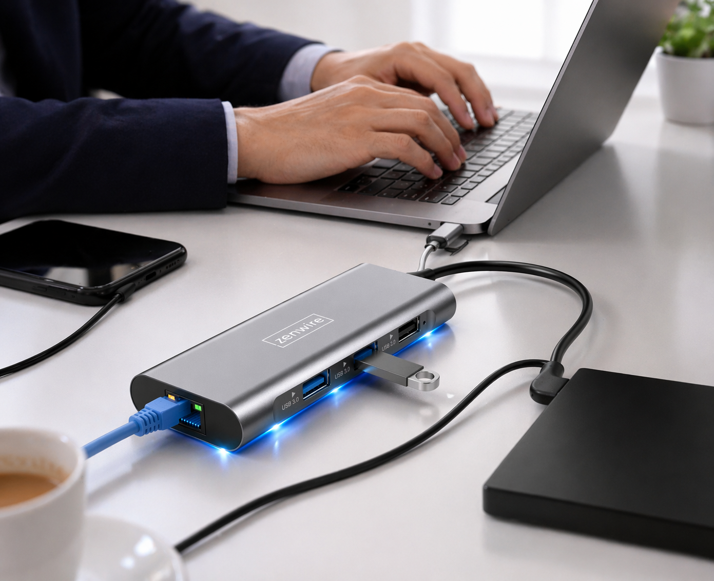 Osoba pisze na laptopie podłączonym do szarego huba USB z niebieskimi światłami.