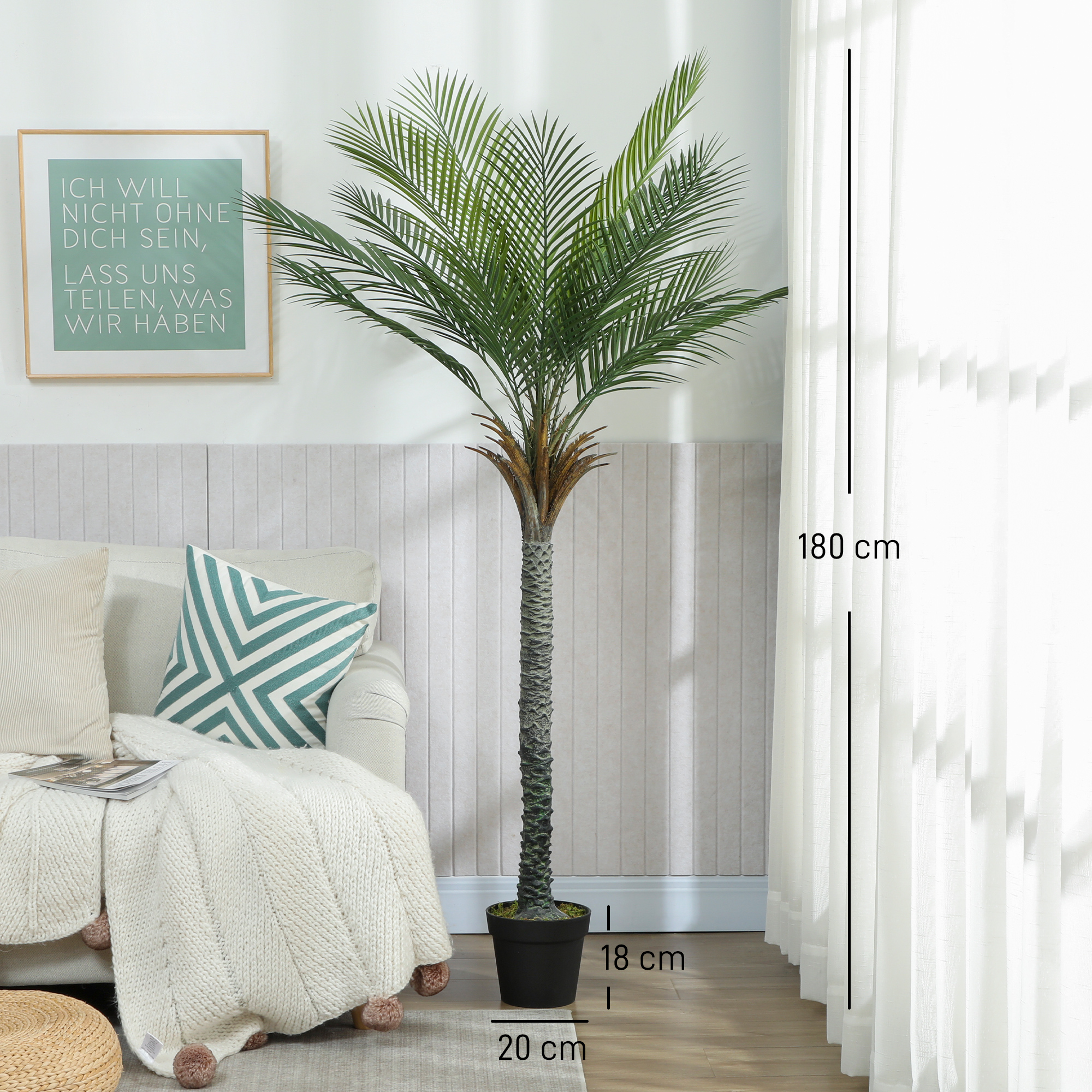 Una palmera artificial alta se encuentra junto a un sofá con cojines y manta.