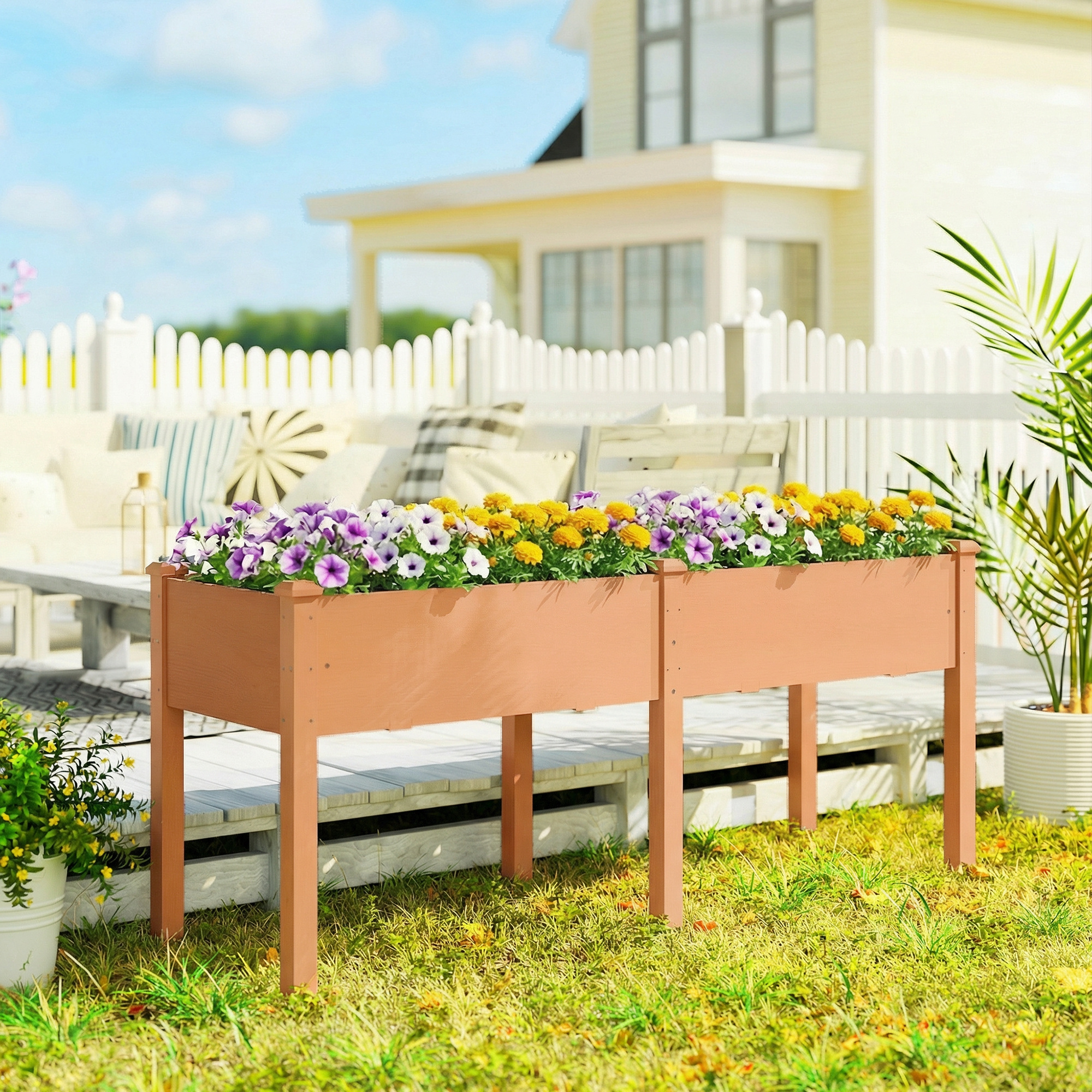 Un bancal elevado de madera con flores moradas y amarillas se asienta en una terraza frente a una casa.