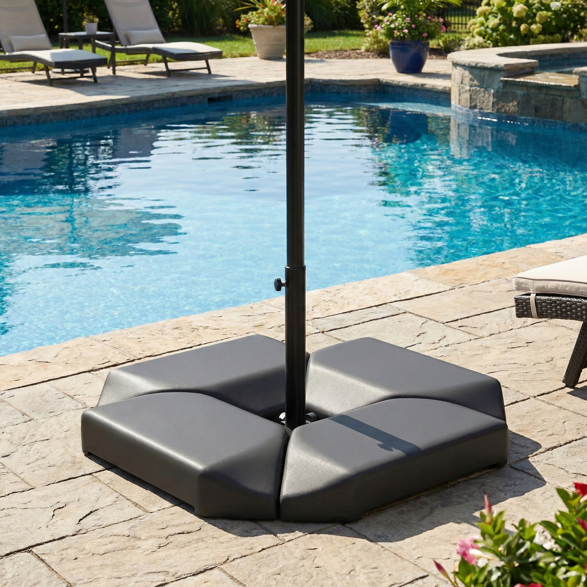Base de sombrilla de patio junto a una piscina con tumbonas al fondo.