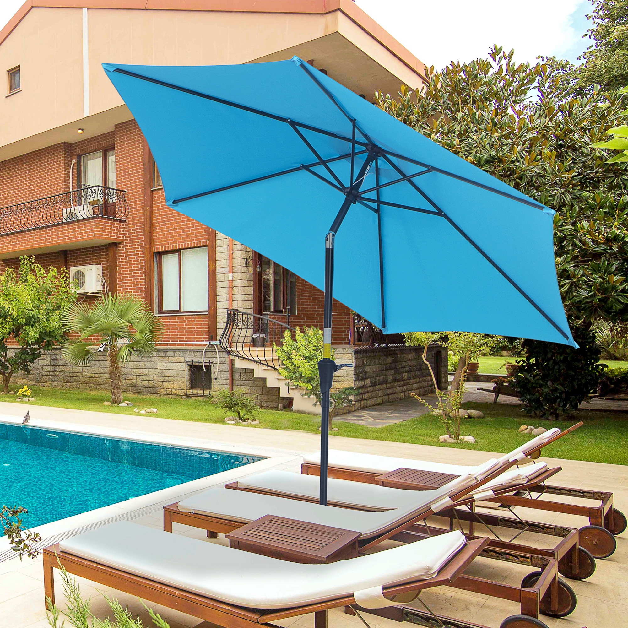Ombrellone blu su sedie a sdraio vicino a piscina e casa in mattoni.
