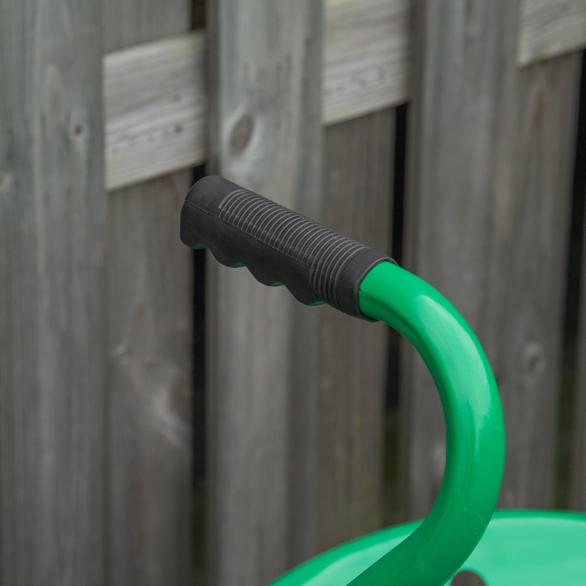 Manillar verde con puño negro delante de una valla de madera.