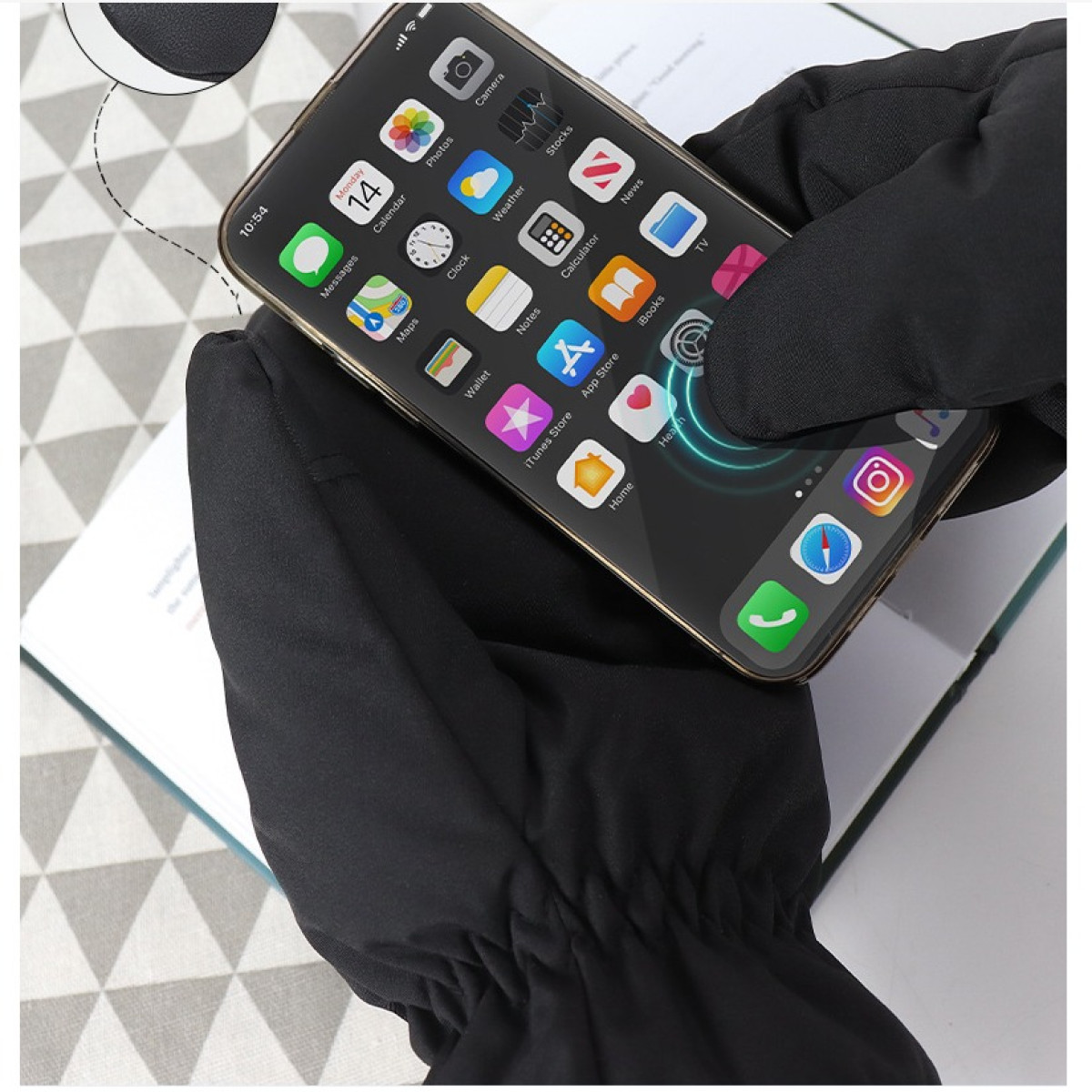 Czarne rękawiczki trzymają smartfon z ikonami różnych aplikacji na ekranie.