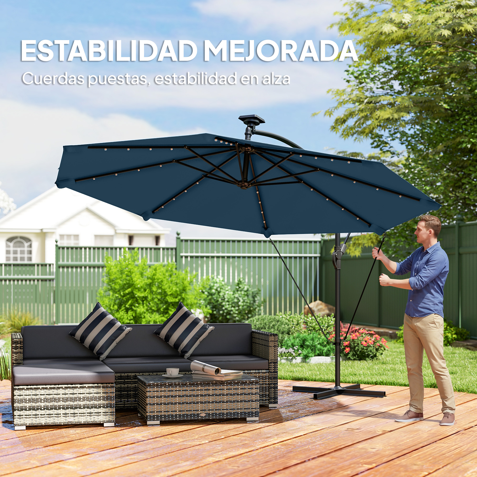 Hombre ajusta sombrilla junto a sofá y mesa en terraza de madera.