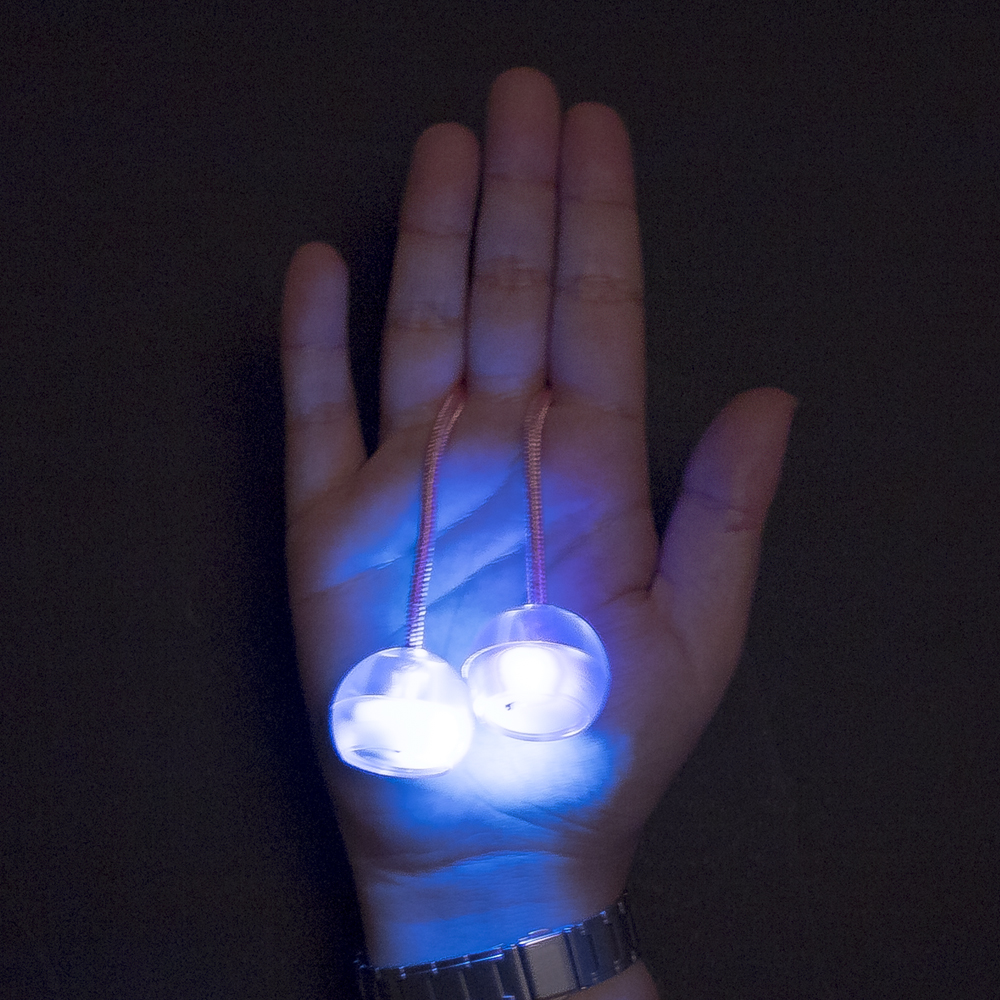 Una mano tiene due palline blu luminose su corde.