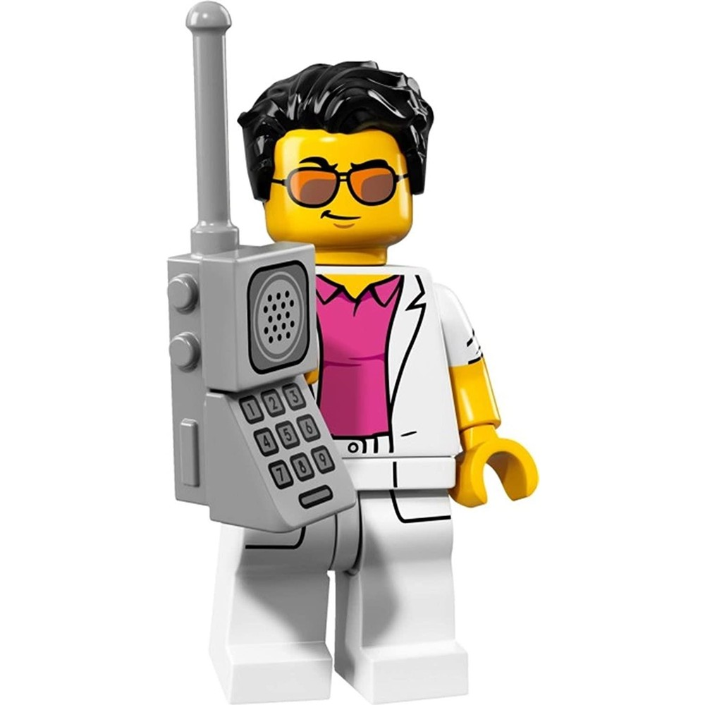 Beyaz takım elbiseli ve pembe gömlekli Lego figürü, gri vintage cep telefonu tutuyor.