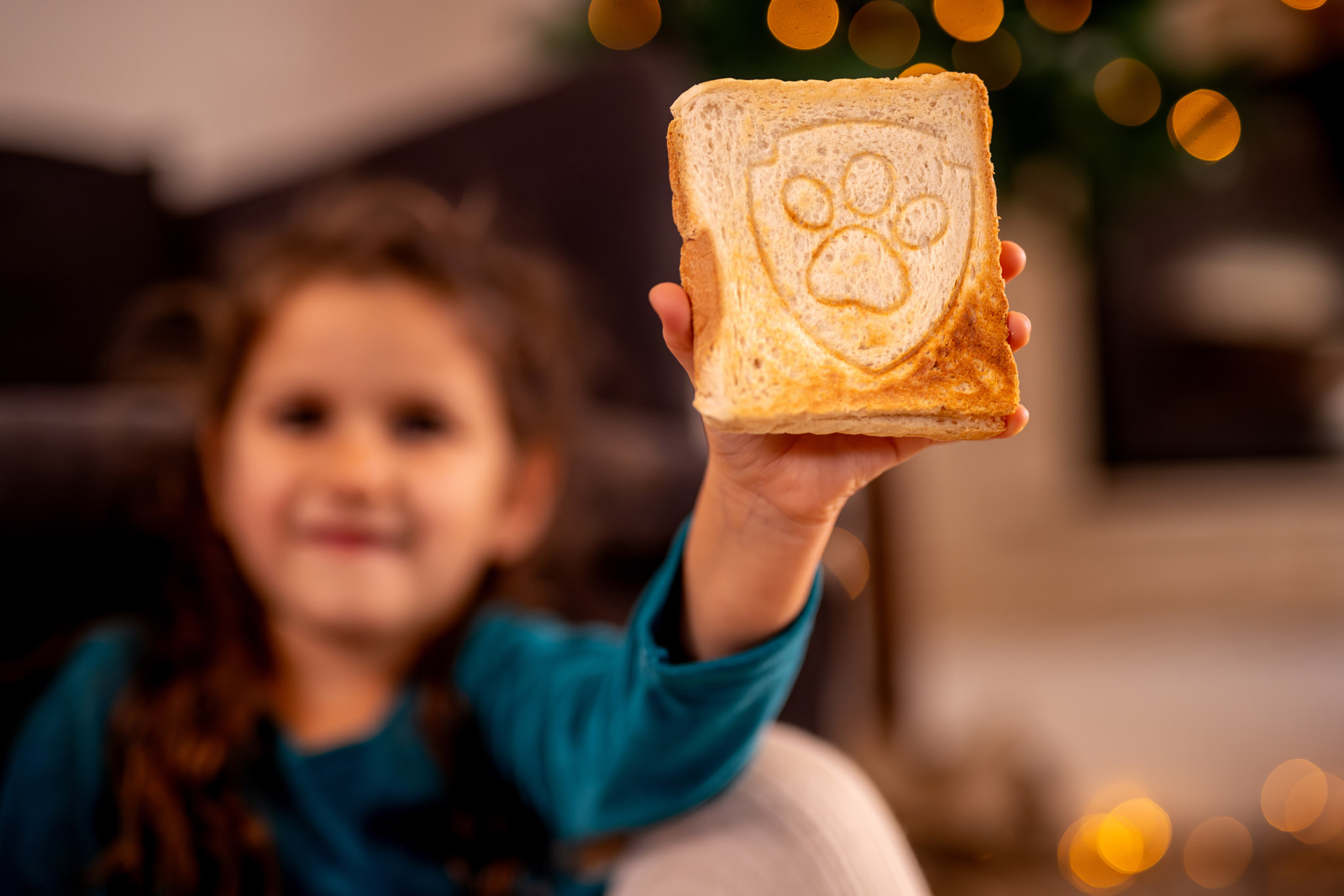 Dziecko trzyma kromkę tost z wzorem łapy. Rozmazane tło.