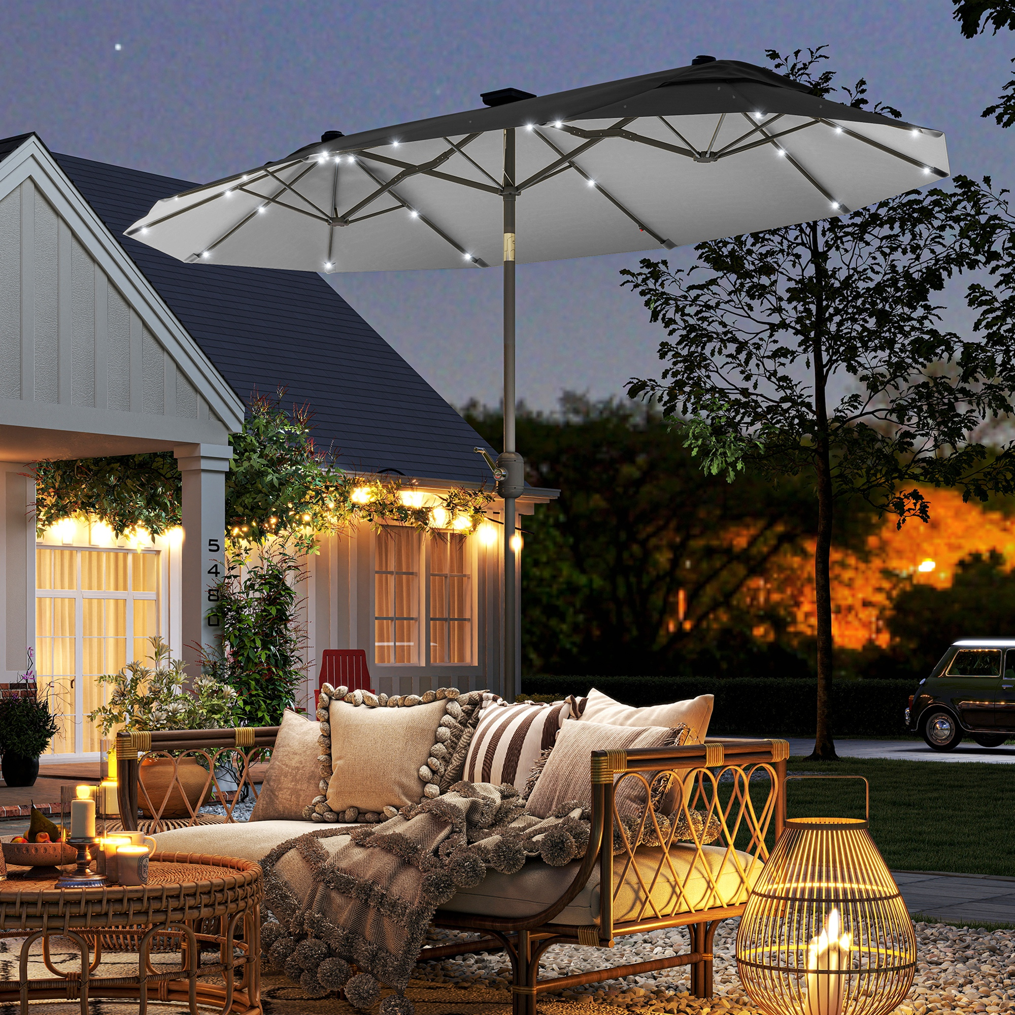 Un patio illuminato di notte con mobili, piante e una casa.