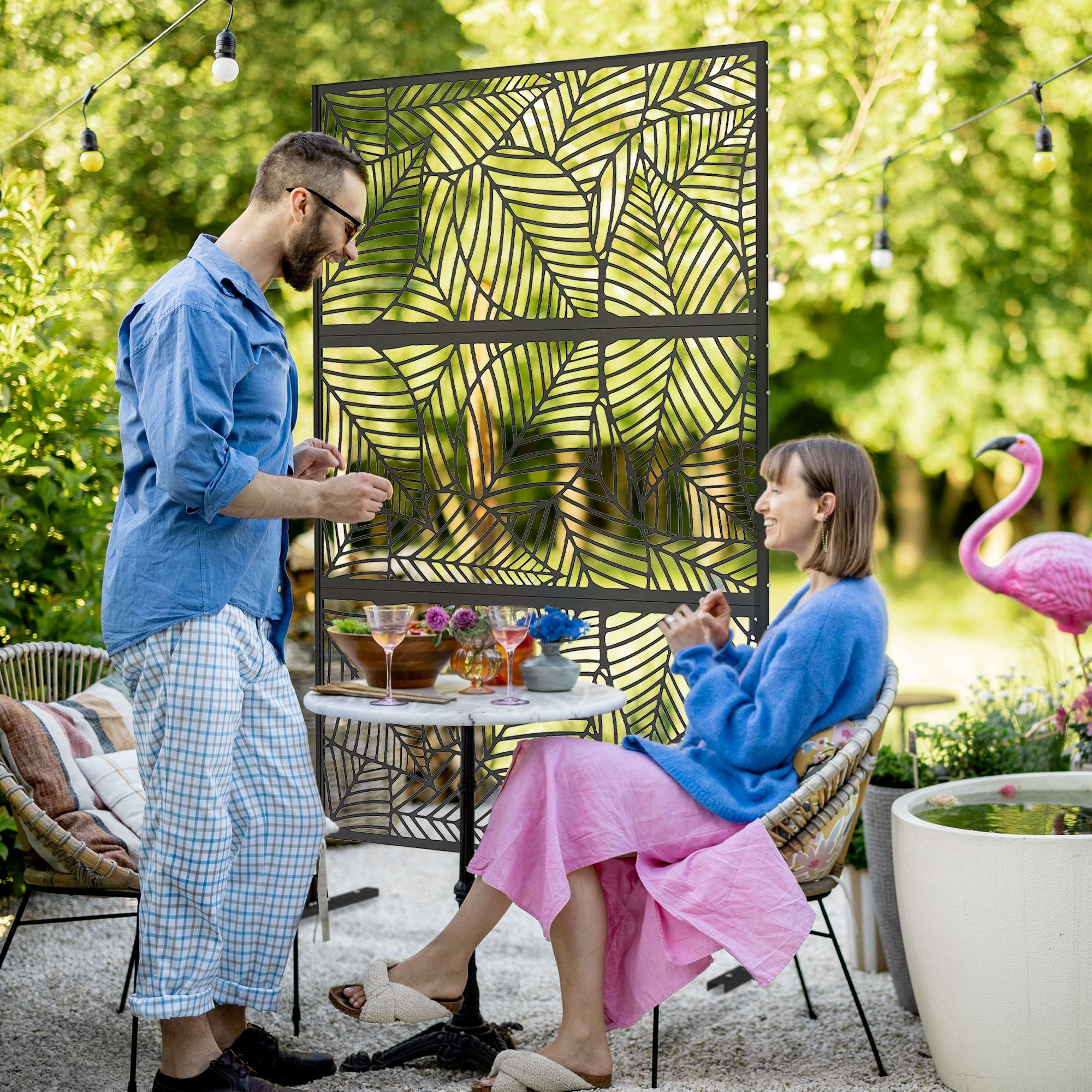 Una pareja relajándose en el jardín con luces de cuerda y una mesa con comida.