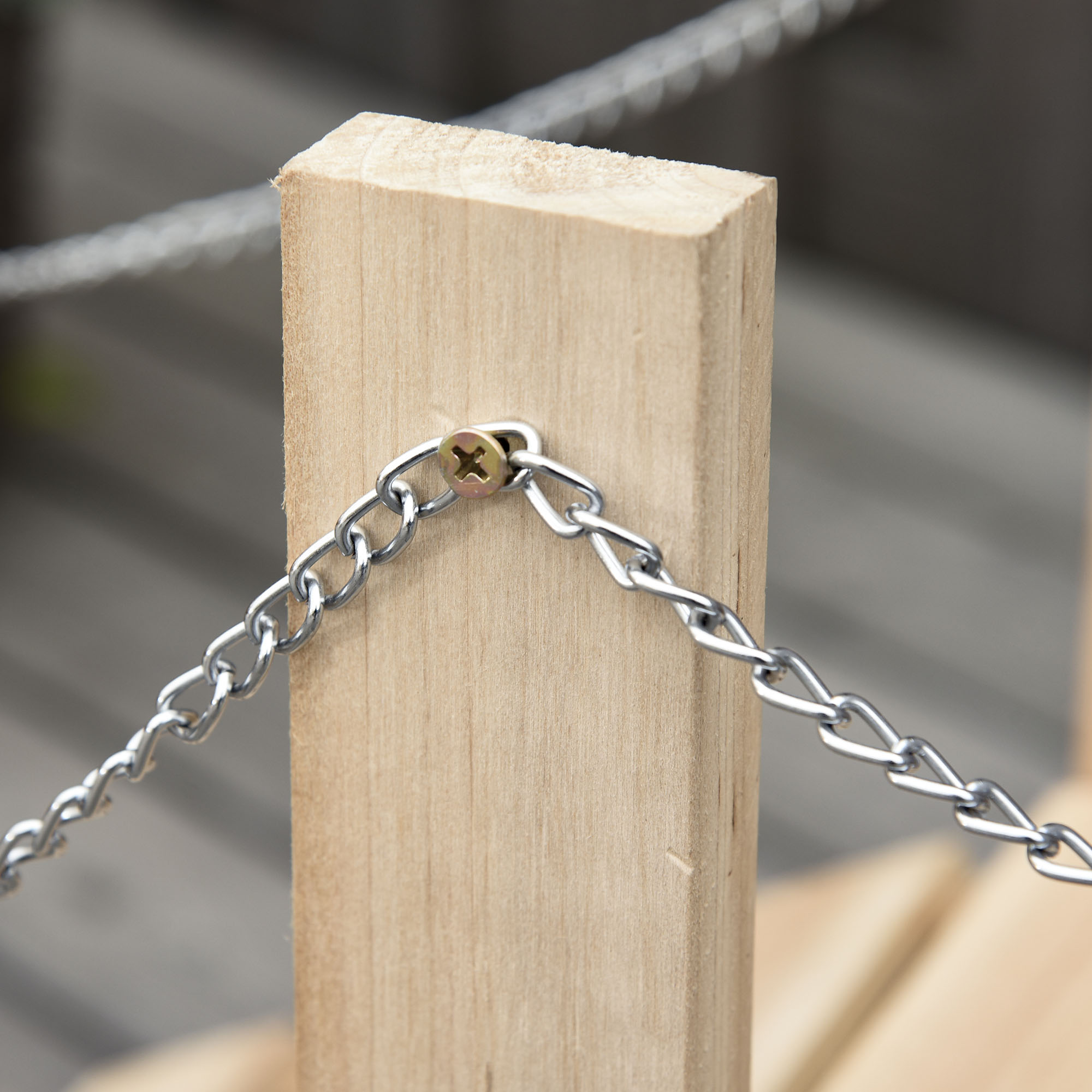 Una cadena plateada está sujeta a un poste de madera con un tornillo.