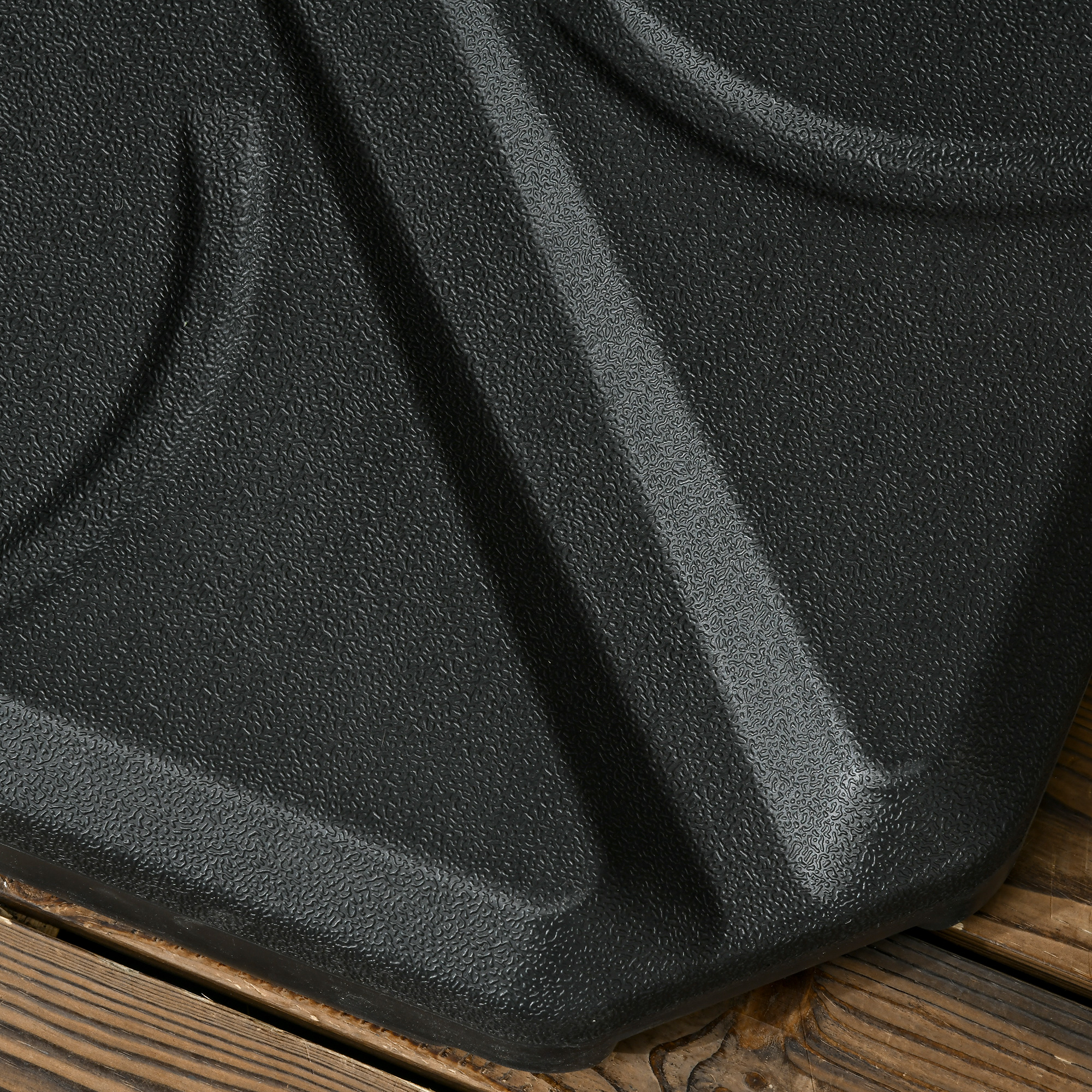Material negro texturizado con pliegues, apoyado sobre tablones de madera.
