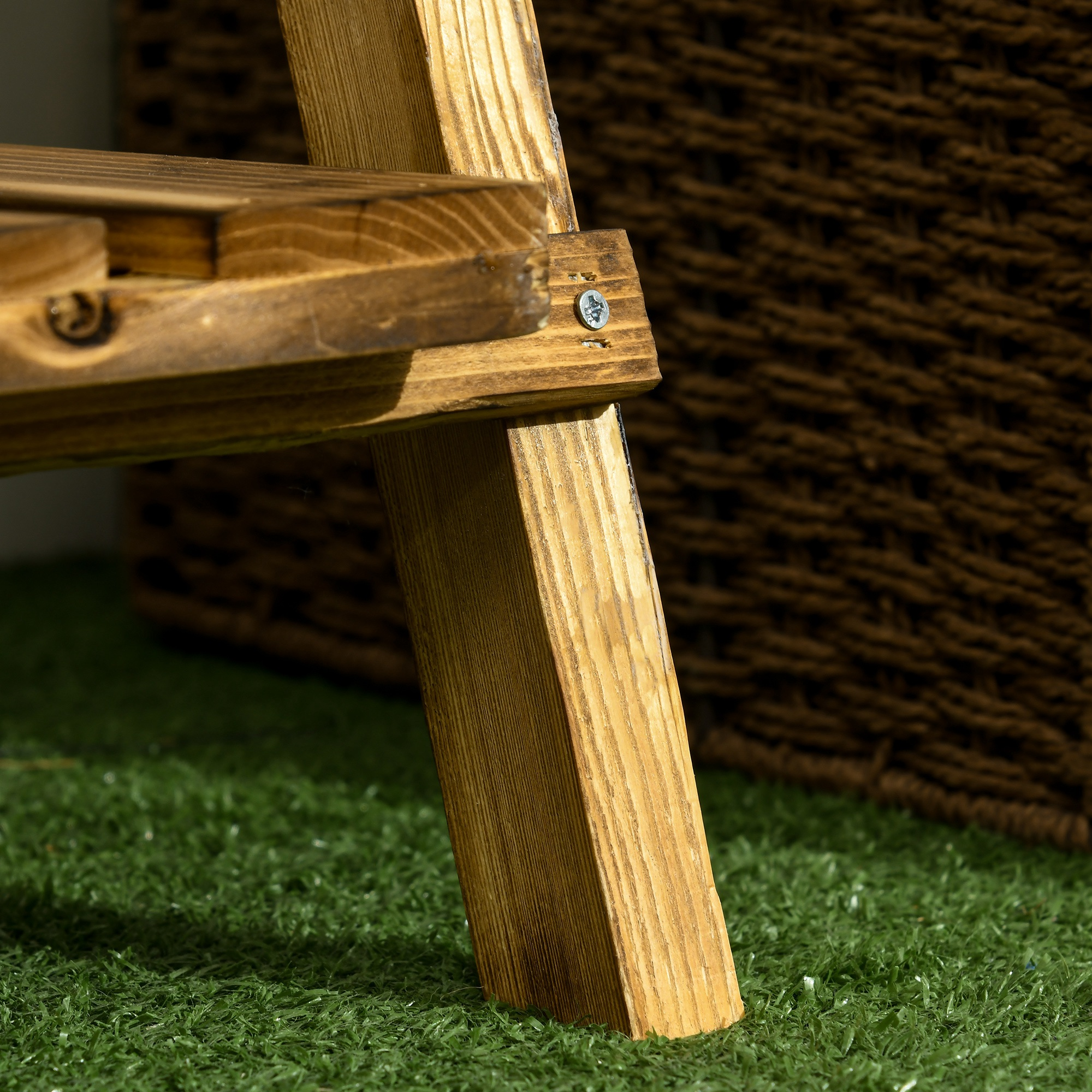 Pata de silla de madera sobre césped artificial frente a una cesta marrón.