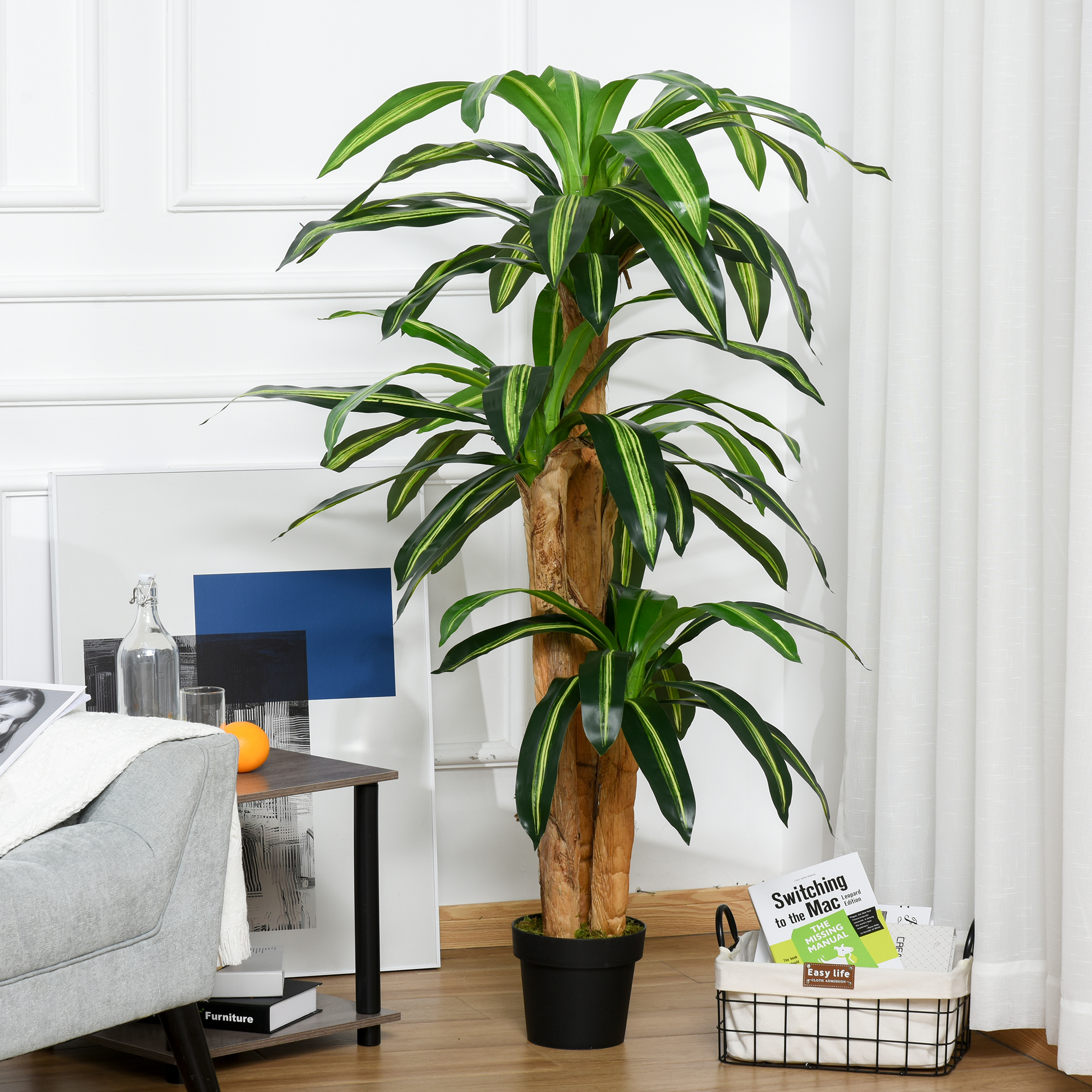 Una planta artificial grande con hojas verdes y amarillas en una maceta negra.