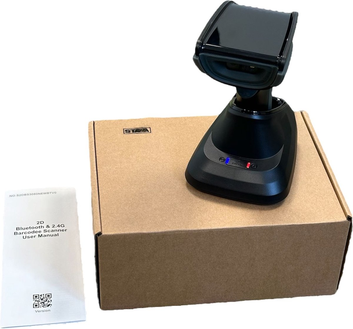 A black barcode scanner on a charging base rests on a cardboard box. A manual is beside it.