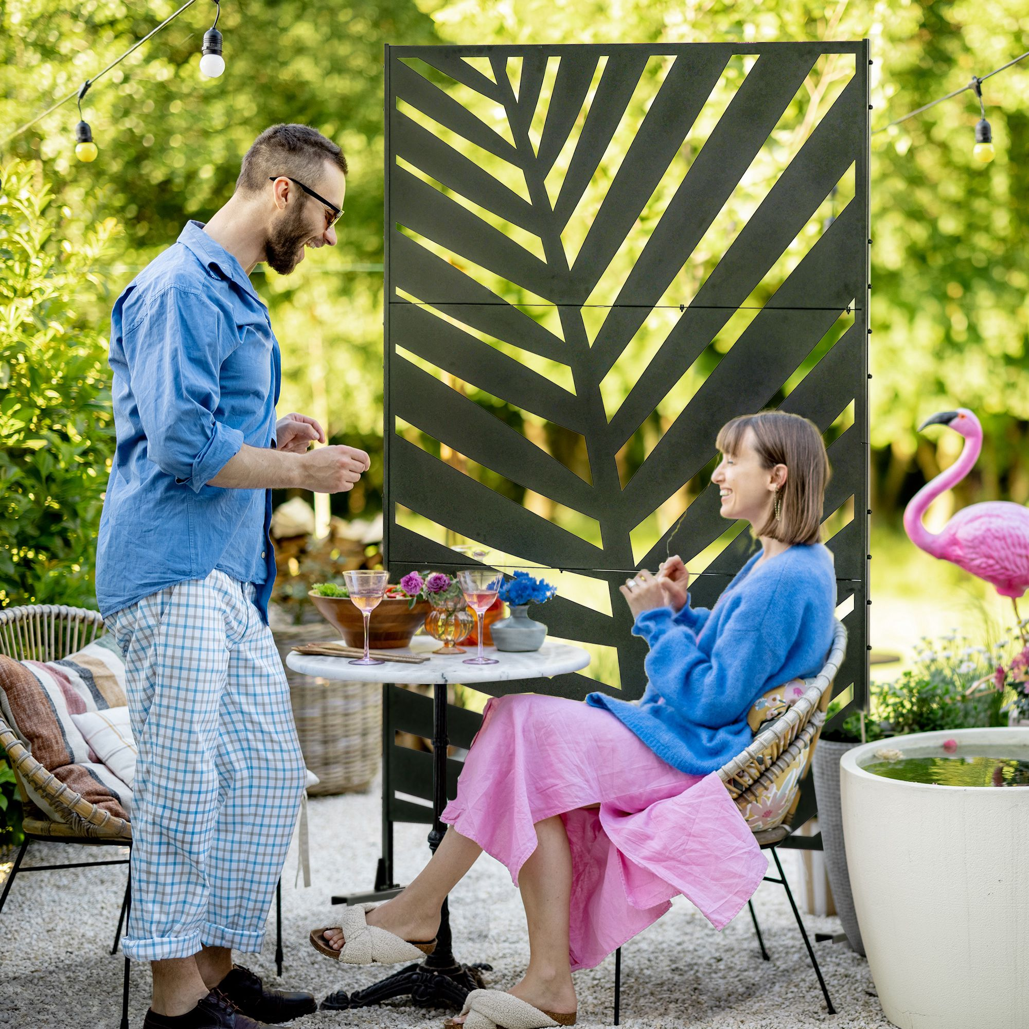 Una pareja se sienta a una mesa en el jardín con comida y bebidas.