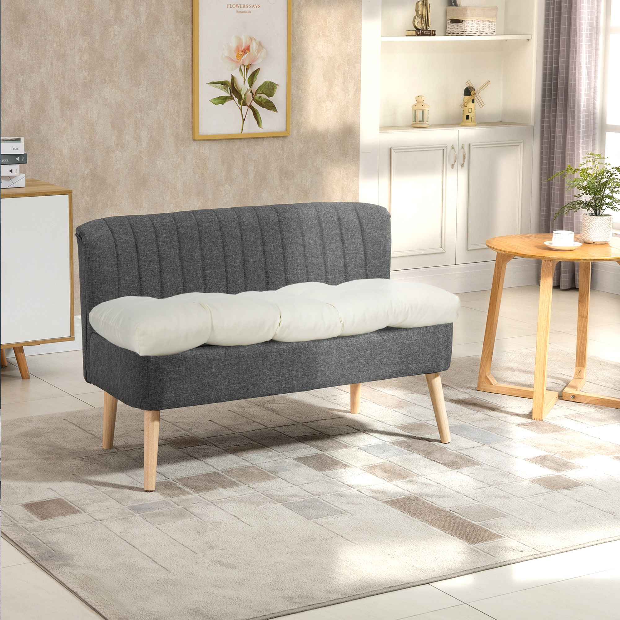 Sofá gris oscuro con cojín blanco frente a pared con cuadro y estante.