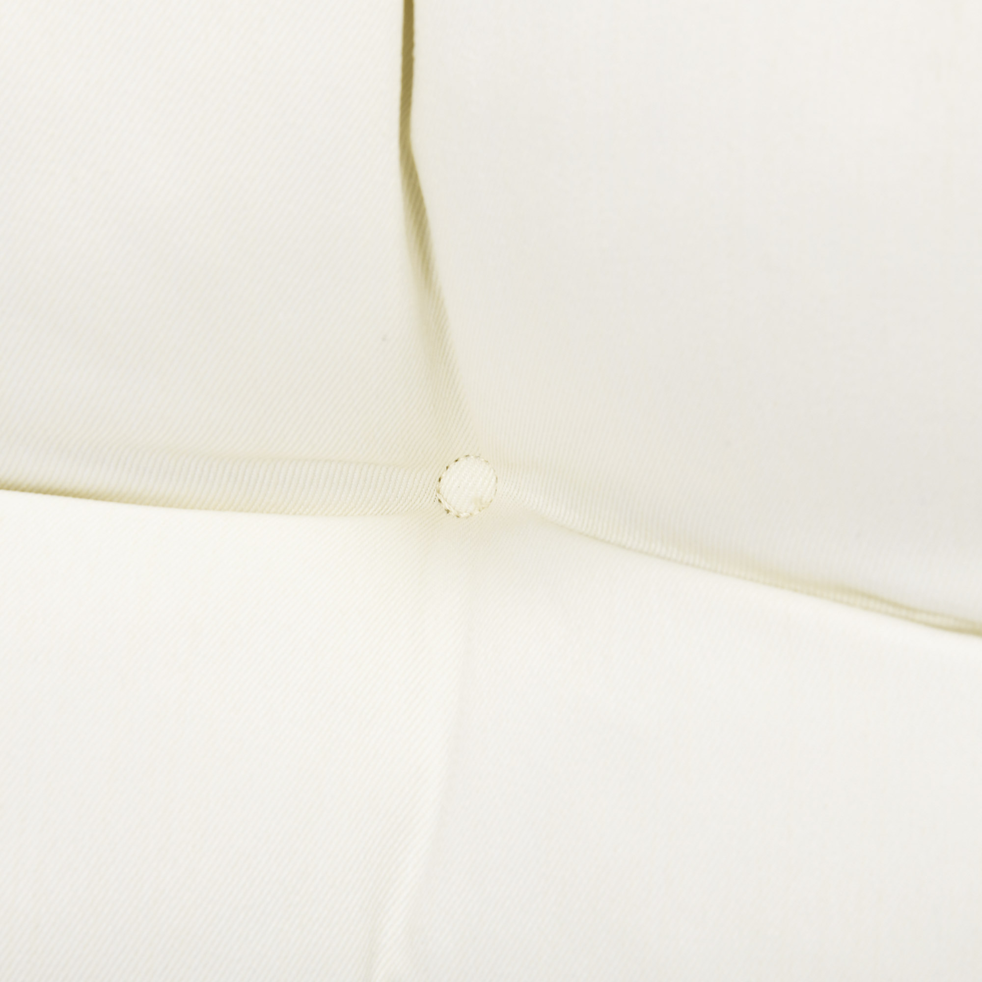 Primer plano de una superficie de tela abombada de color crema con un botón visible.