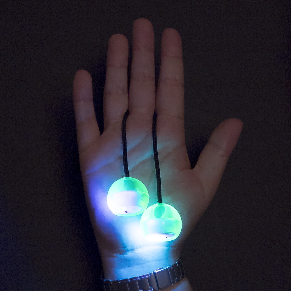 Una mano tiene due sfere luminose su corde, illuminate da luce blu e verde.