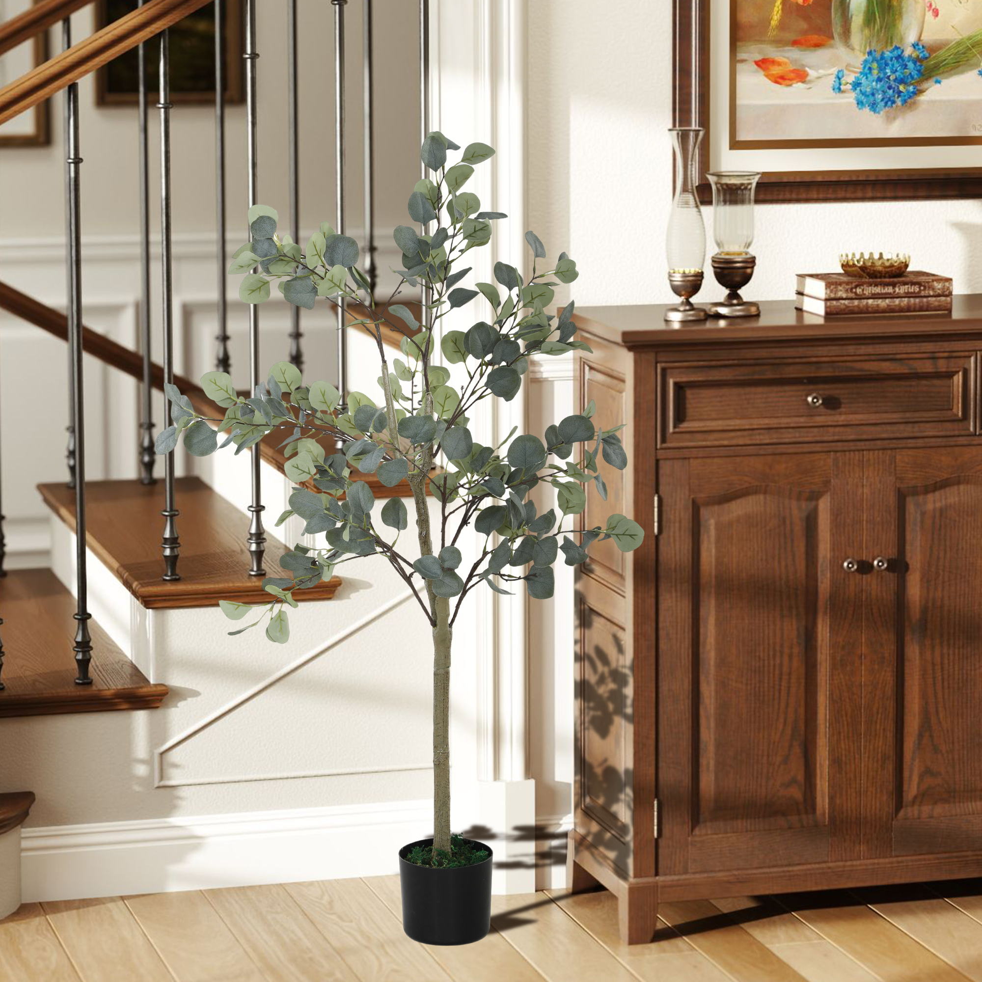 Una planta de eucalipto verde en maceta está junto a una escalera de madera y un armario.