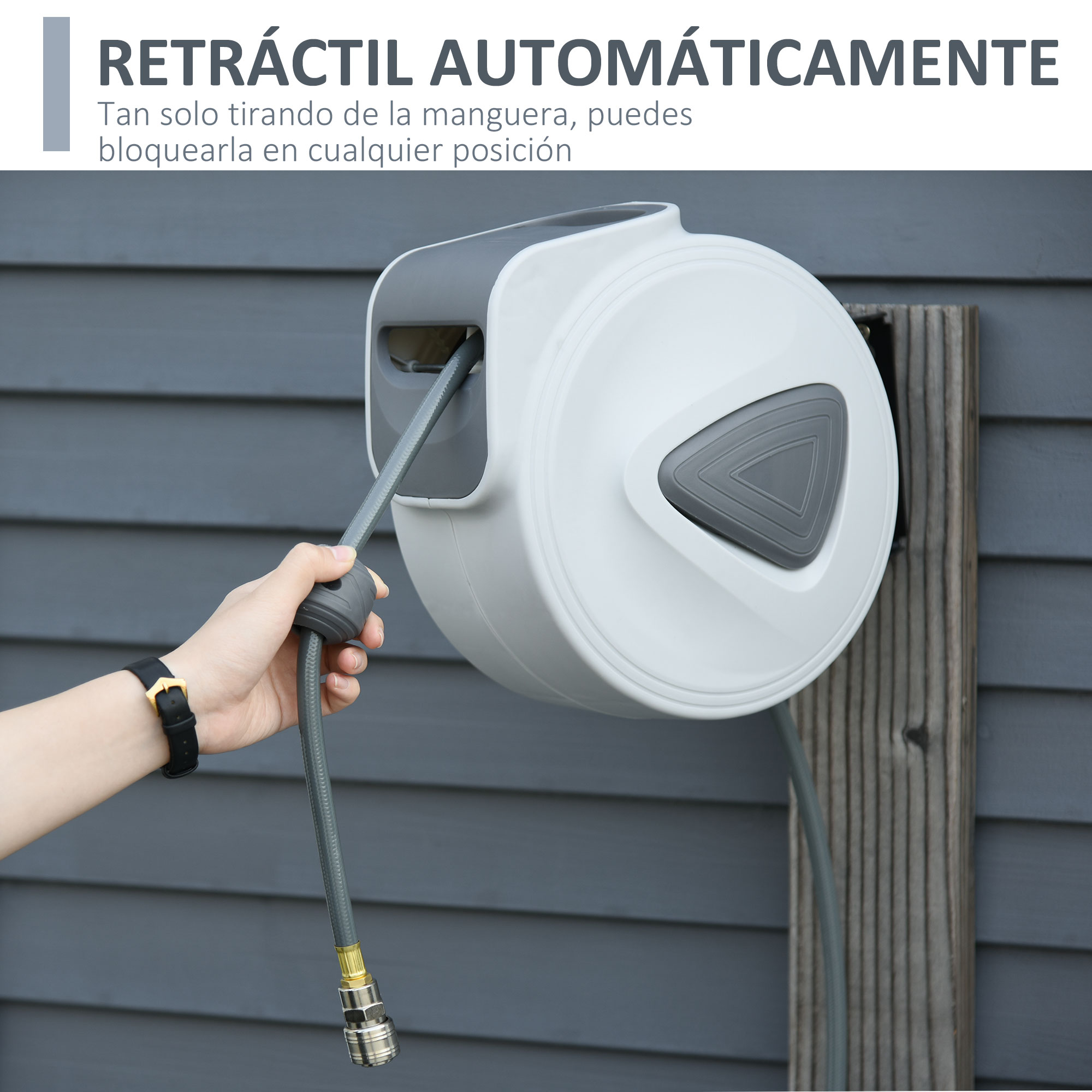 Una mano sujeta una manguera de jardín gris que sale de un enrollador automático blanco.