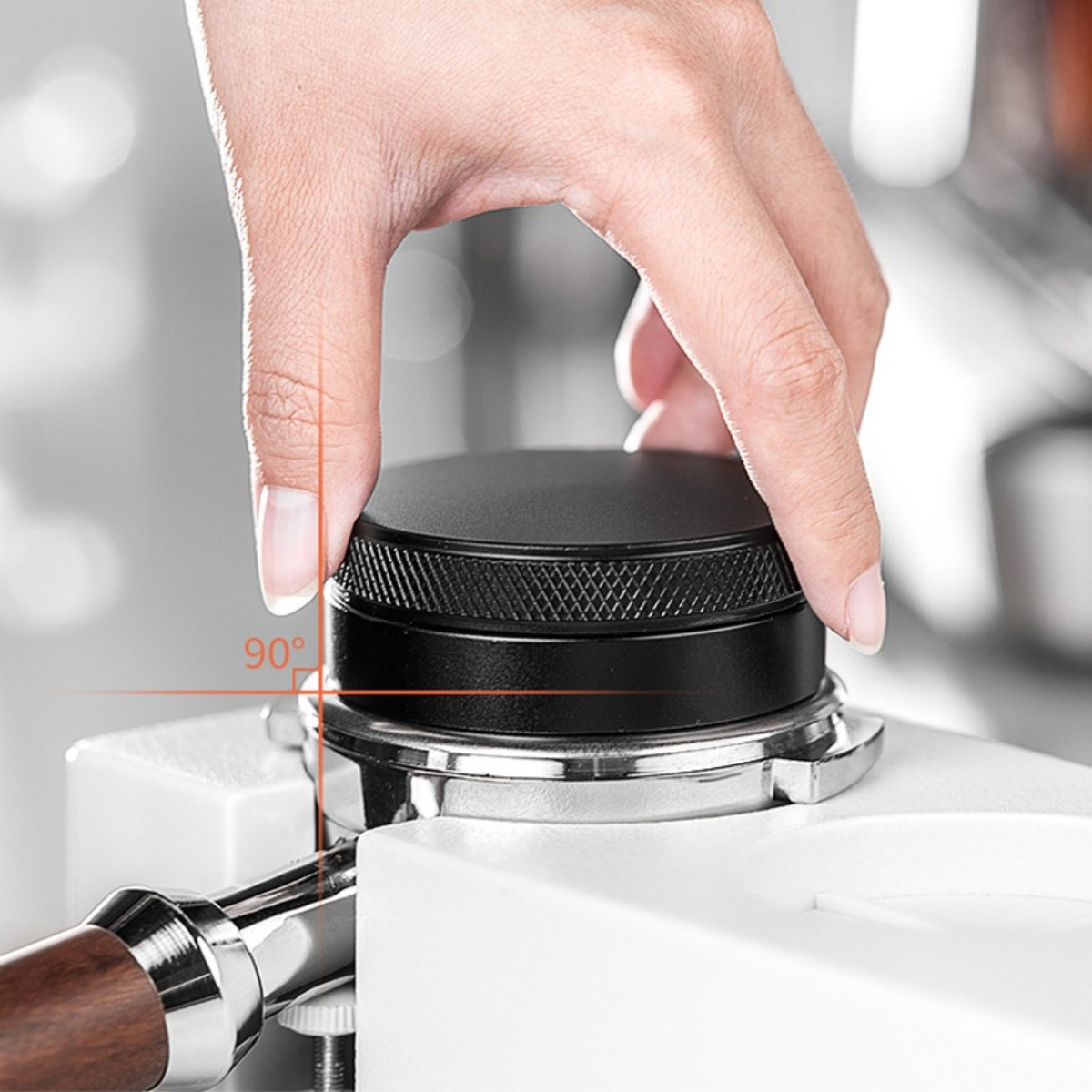 Una mano preme un tamper nero su un portafiltro da caffè.