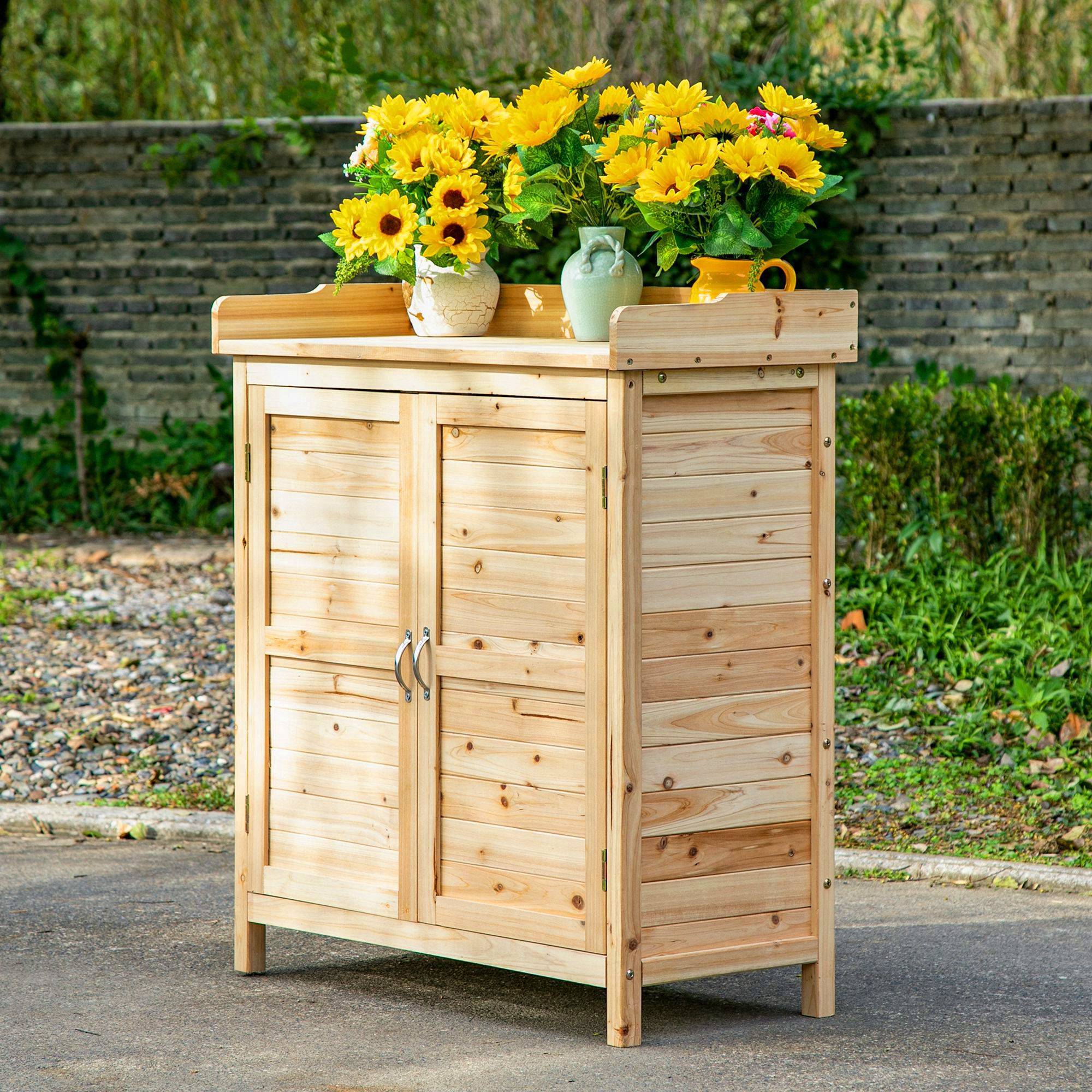 Un armario de madera con girasoles y jarrones al aire libre.