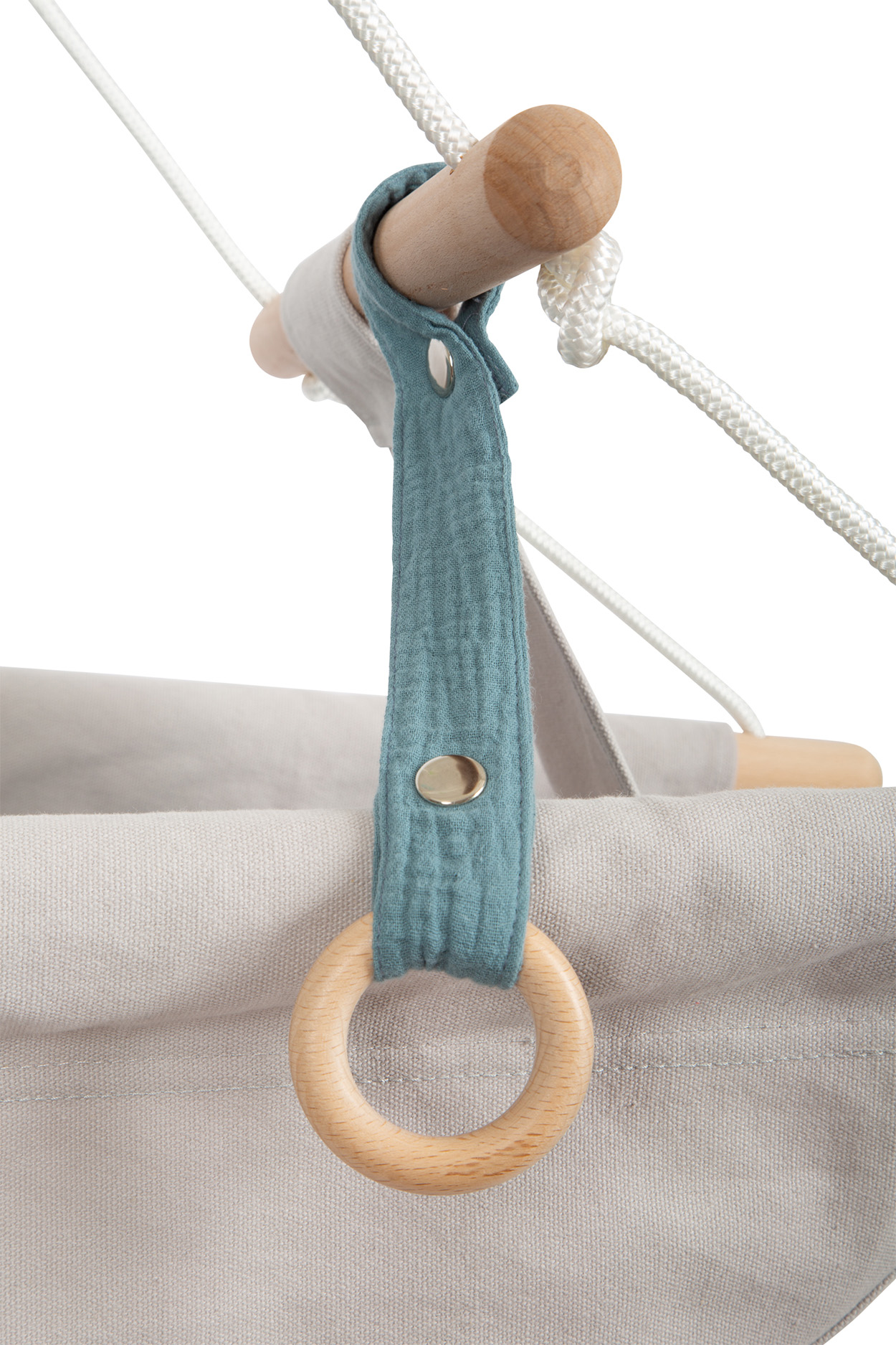Ein hölzerner Ring hängt an einem blauen Stoffband, das an einem Holzstab befestigt ist.