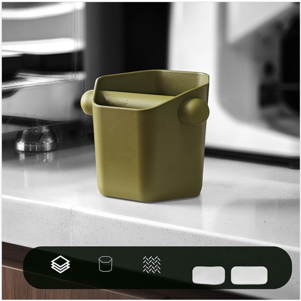 Un contenitore verde per fondi di caffè con due manici poggia su un piano di lavoro maculato.